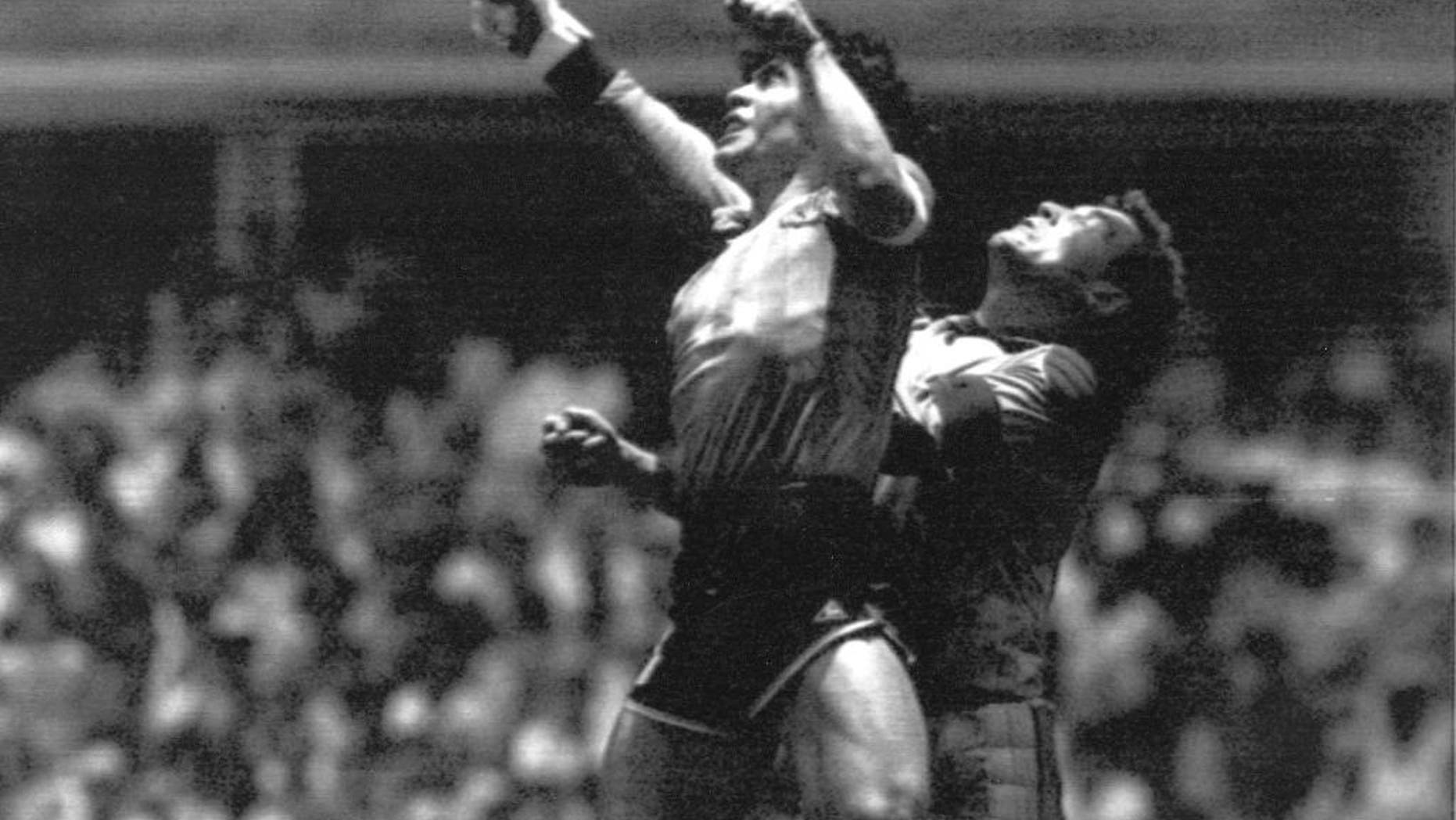 FILE - This is a Sunday, June 22, 1986 file photo of Argentina's Diego Maradona, left, as he is seen in the controversial action in which he knocked the ball with his left hand into the net of England's goalie Peter Shilton to score his team's first goal when Argentina defeated England 2-1 in the World Cup quarterfinal in the Mexico City Aztec stadium. Cheating. It's an ugly side of the beautiful game and it involves just about every aspect of it. The World Cup in Brazil begins in June and the founders of association football would shudder at how entrenched deception and trickery have become in the modern game. (AP Photo/El Grafico, File)