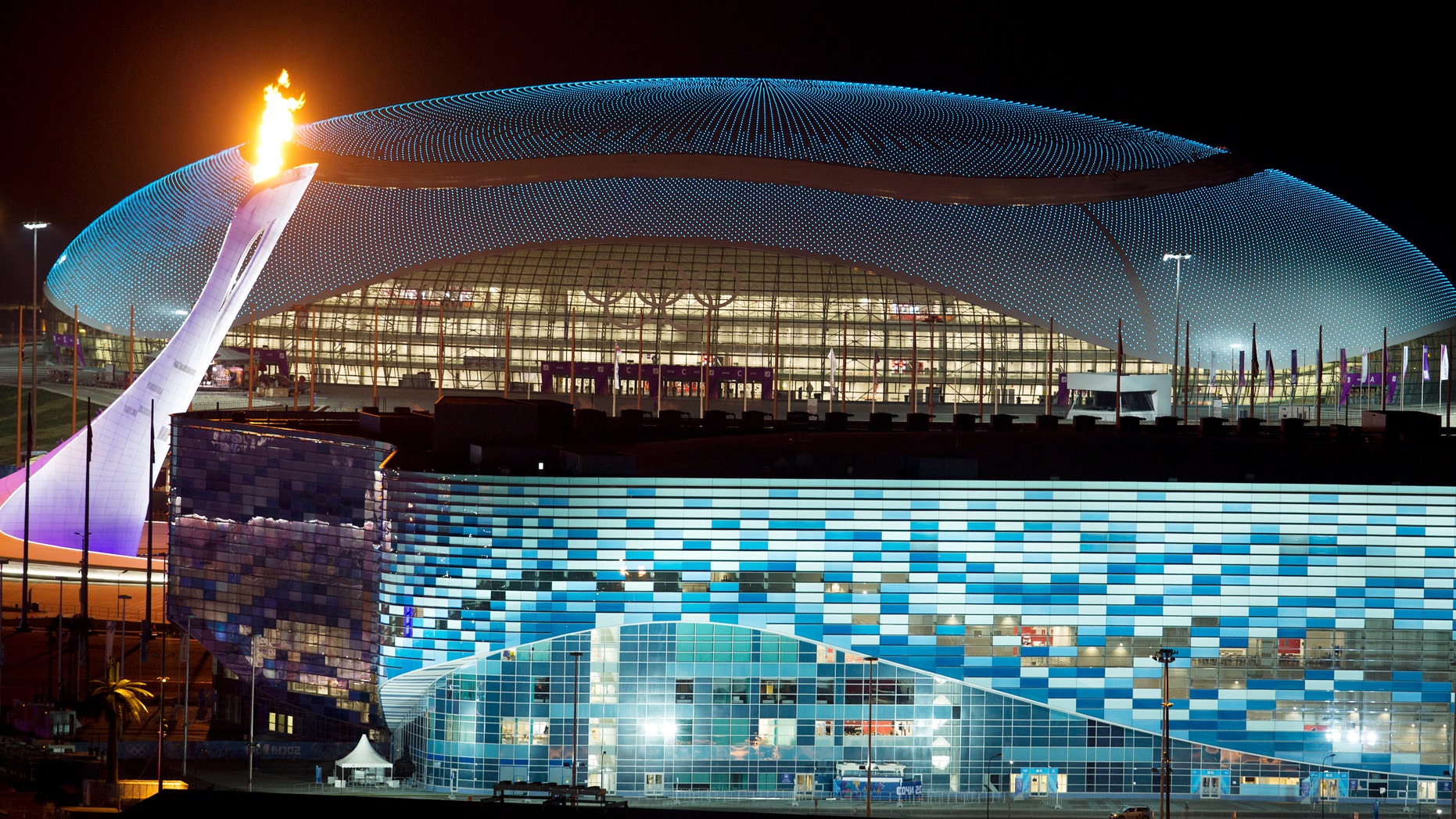 FILE - In this Thursday, Feb. 6, 2014 file photo, the Olympic cauldron, left, is lit during a test between the Bolshoy Ice Dome, top, and the Iceberg Skating Palace, foreground, in Sochi, Russia, prior to the start of the 2014 Winter Olympics. Westerners coming to Sochi for the Olympic games seemed surprised by the unfinished hotels, packs of stray dogs, and warnings not to drink the strange-colored water. But these vivid problems aside, the Olympics and ancillary development show some promising signs for the country. (AP Photo/Pavel Golovkin, File)