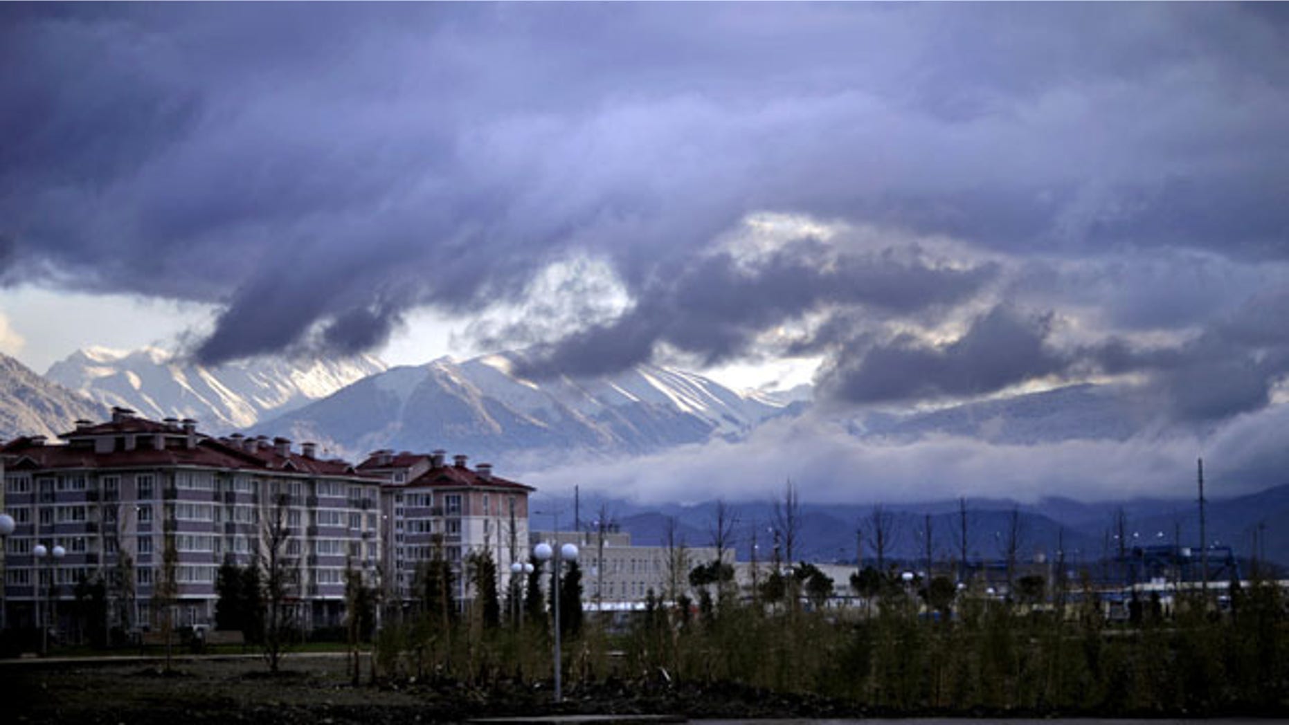 February 1, 2014: The Caucasus Mountains, site of the 2014 Winter Olympic outdoor snow sport and sliding track events, rise above a recently built housing complex, at left, near the Olympic Park by the Black Sea in the Coastal Cluster in Sochi, Russia. (AP Photo/David Goldman)