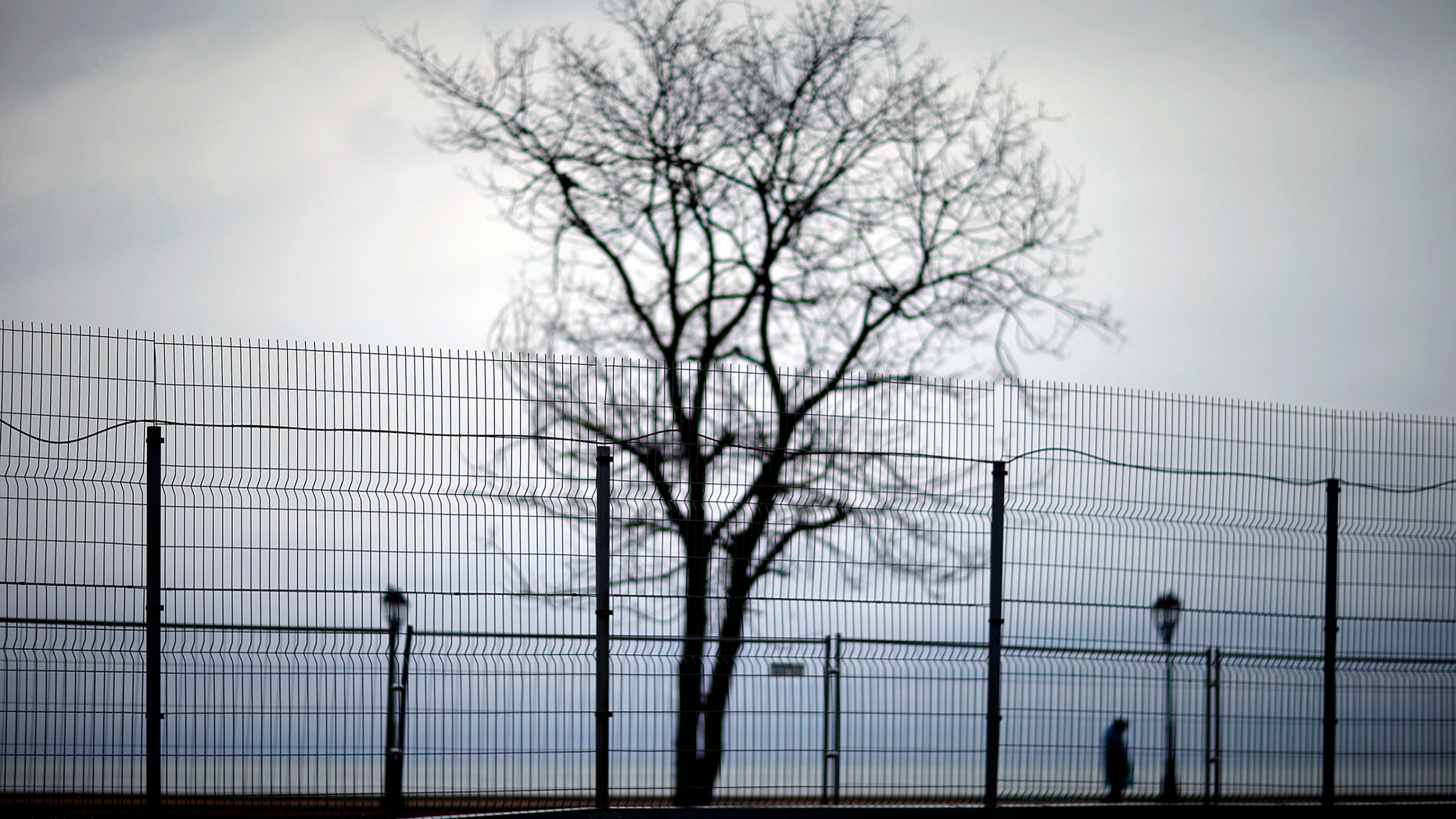 Jan. 31, 2014 - A security fence lines the perimeter of the Olympic Park as a policeman at right patrols along the boardwalk on the Black Sea ahead of the 2014 Winter Olympics in Sochi, Russia.