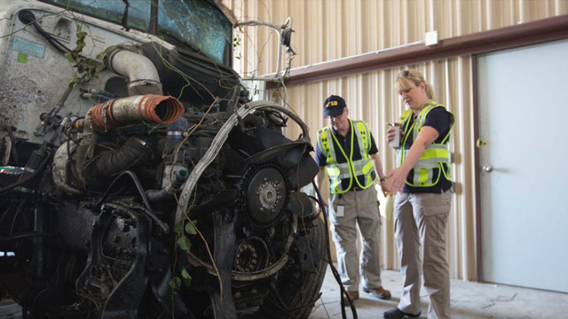 September 27, 2014: In this photo provided by The National Transportation Safety Board, officials examine part of the wreckage involved in a fatal highway accident in Davis, Okla. (AP Photo/National Transportation Safety Board)
