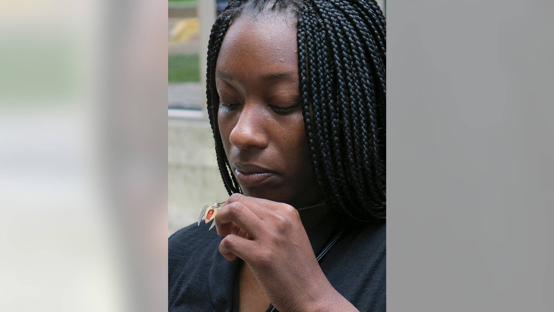FILE - This April 24, 2014, file photo shows Tarshia Williams displaying a pendant with her daughter, Talia's face on it outside of a federal courthouse in Honolulu. Jurors have reached a decision about whether a former Hawaii soldier is eligible for the death penalty, in the first capital case in the history of Hawaii's statehood. The jury last month convicted Naeem Williams of murder in his daughter Talia's 2005 beating death. The same jurors were then asked to determine whether Williams can be sentenced to death. (AP Photo/Sam Eifling, File)