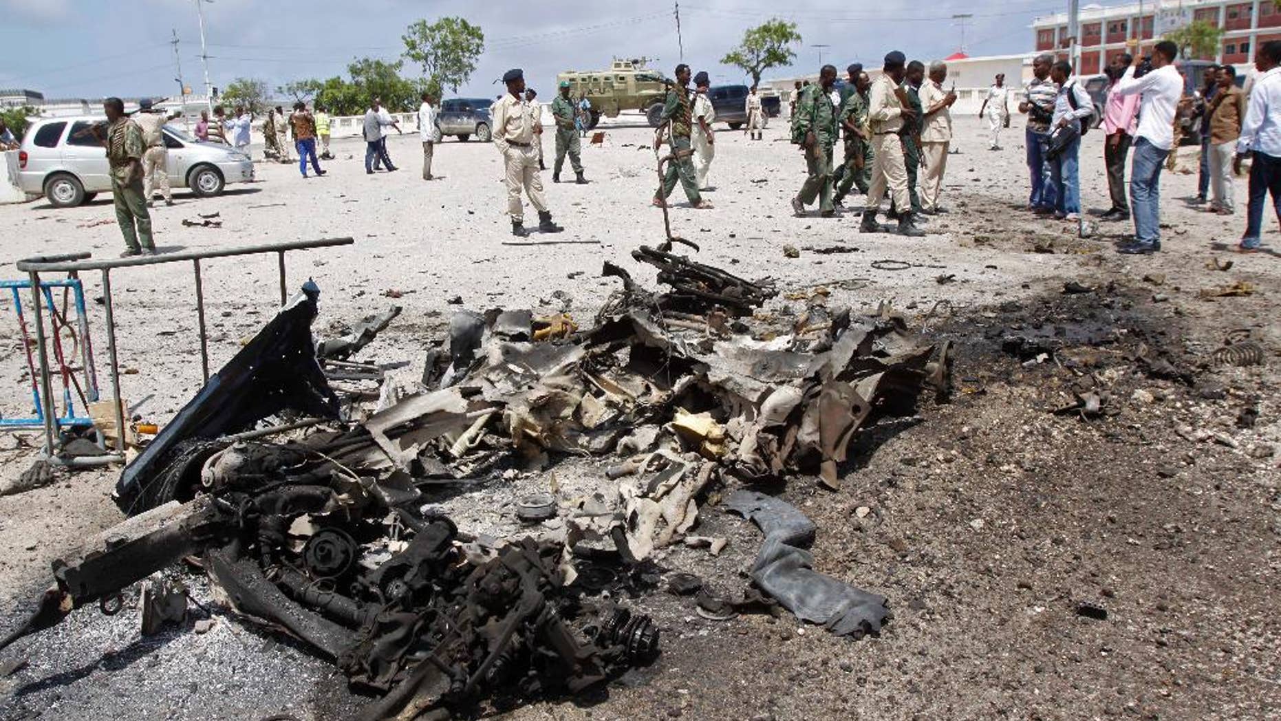 Somali soldiers stand near the wreckage of a suicide car bomb near the Somali parliament in Mogadishu, Somalia, Saturday, July 5, 2014. A Somali police officer says troops have thwarted an attack by a suicide bomber outside the heavily guarded parliament headquarters. Capt. Mohamed Hussein, a senior Somali police officer says troops stopped a suicide car bomber who detonated his explosive-laden car at a checkpoint near the entrance to Somalia's parliament. (AP Photo/Farah Abdi Warsameh)