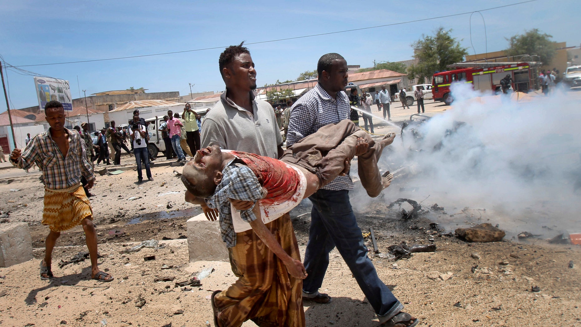 March 18, 2013 - Somali men carry a seriously wounded man after a car bomb blast close to the Somali government's headquarters in the capital Mogadishu, Somalia.