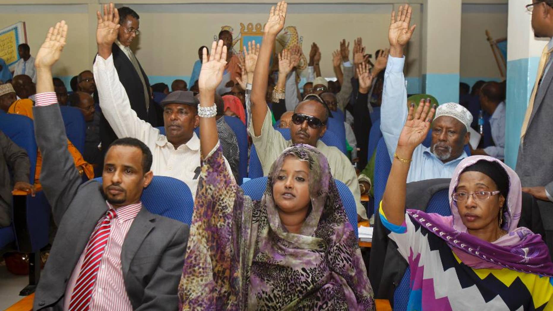 Somali lawmakers raise their hands to vote during a parliament session to impeach Somali Prime Minister Abdiweli Sheikh Ahmed, who lost the no-confidence vote in Mogadishu, Somalia, Saturday, Dec. 6, 2014. The speaker of Somalia's parliament says that the body of legislators has voted to oust the country's prime minister Abdiweli Sheikh Ahmed from office, with the vote taking place after several recent rowdy sessions of parliament over the issue. (AP Photo/Farah Abdi Warsameh)