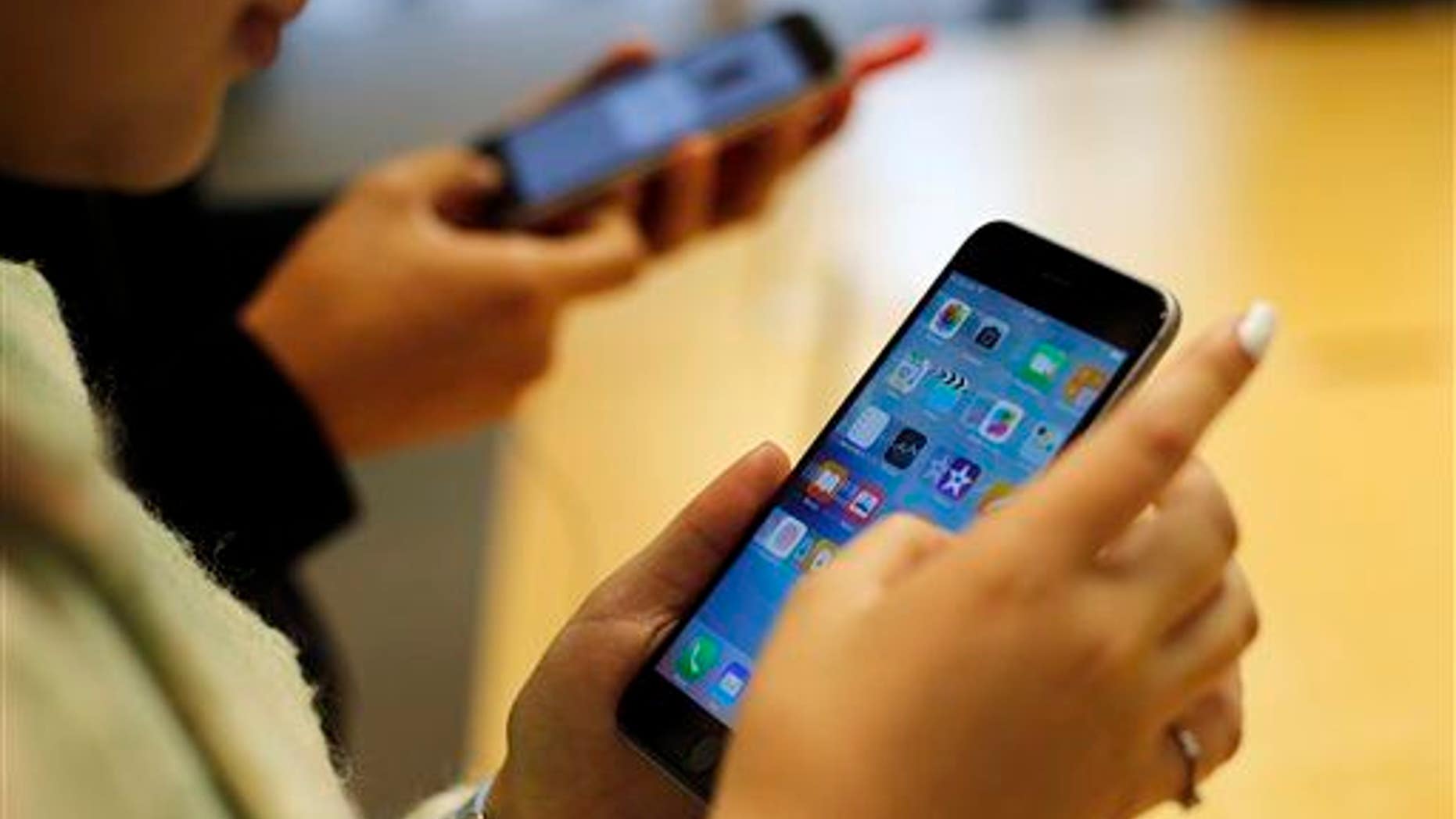 Customers try out a new Apple iPhone 6S at an Apple store on Chicago's Magnificent Mile, Friday, Sept. 25, 2015, in Chicago.