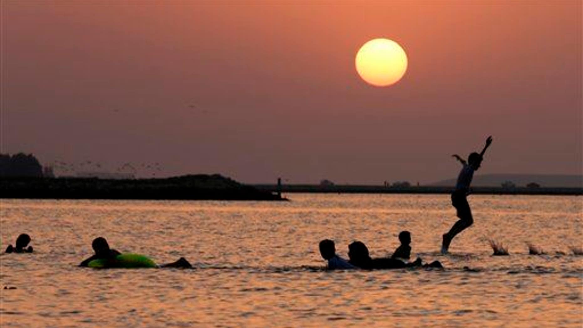 Bahraini children play along the Persian Gulf shore as the sun sets in Karranah, Bahrain, on Sept. 20, 2014.