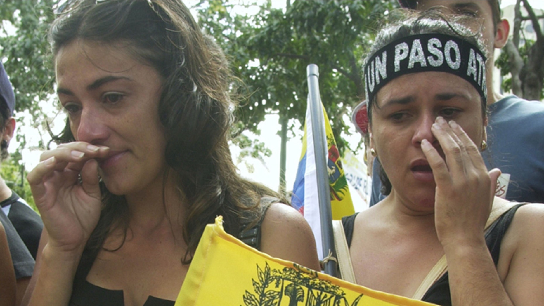 CARACAS, VENEZUELA - DECEMBER 7: Two woman cry near the site where a demonstrator was killed December 7, 2002 at Plaza Francia in Caracas, Venezuela. The demonstrator was killed December 6, 2002 when gunmen opened fire during an opposition rally killing at least three and injuring 28. (Photo by Oscar Sabetta/Getty Images)