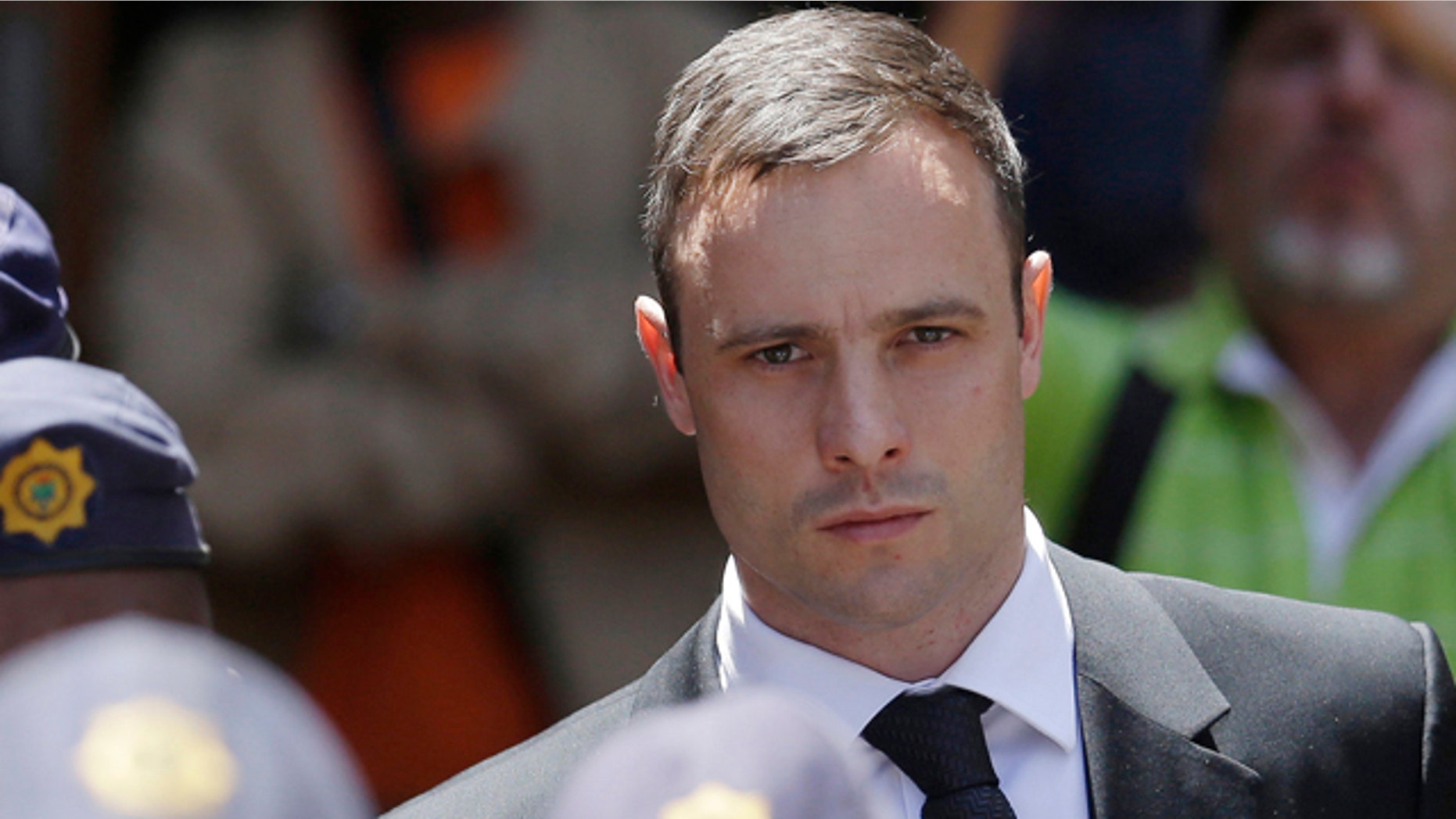 FILE - In this Friday, Oct. 17, 2014 file photo, Oscar Pistorius is escorted by police officers as he leaves the high court in Pretoria, South Africa. (AP Photo/Themba Hadebe, File)