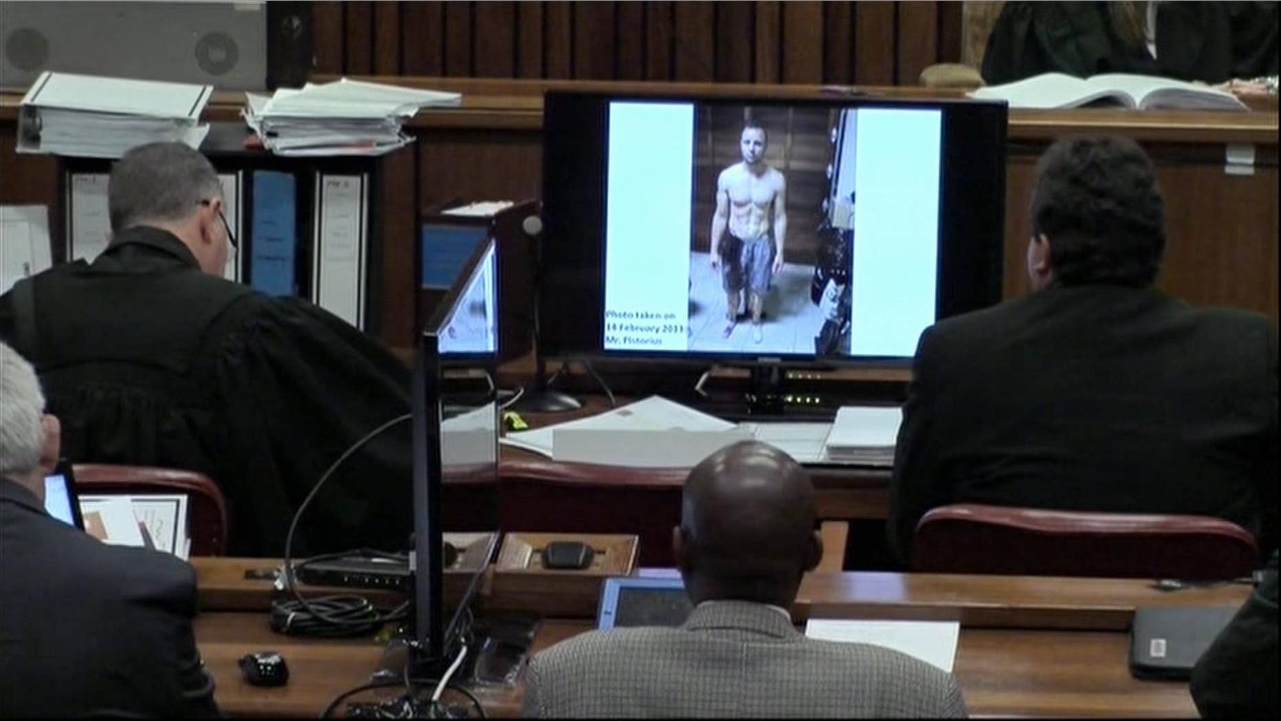 A police photograph of Oscar Pistorius standing on his blood-stained prosthetic legs and wearing shorts covered in blood.