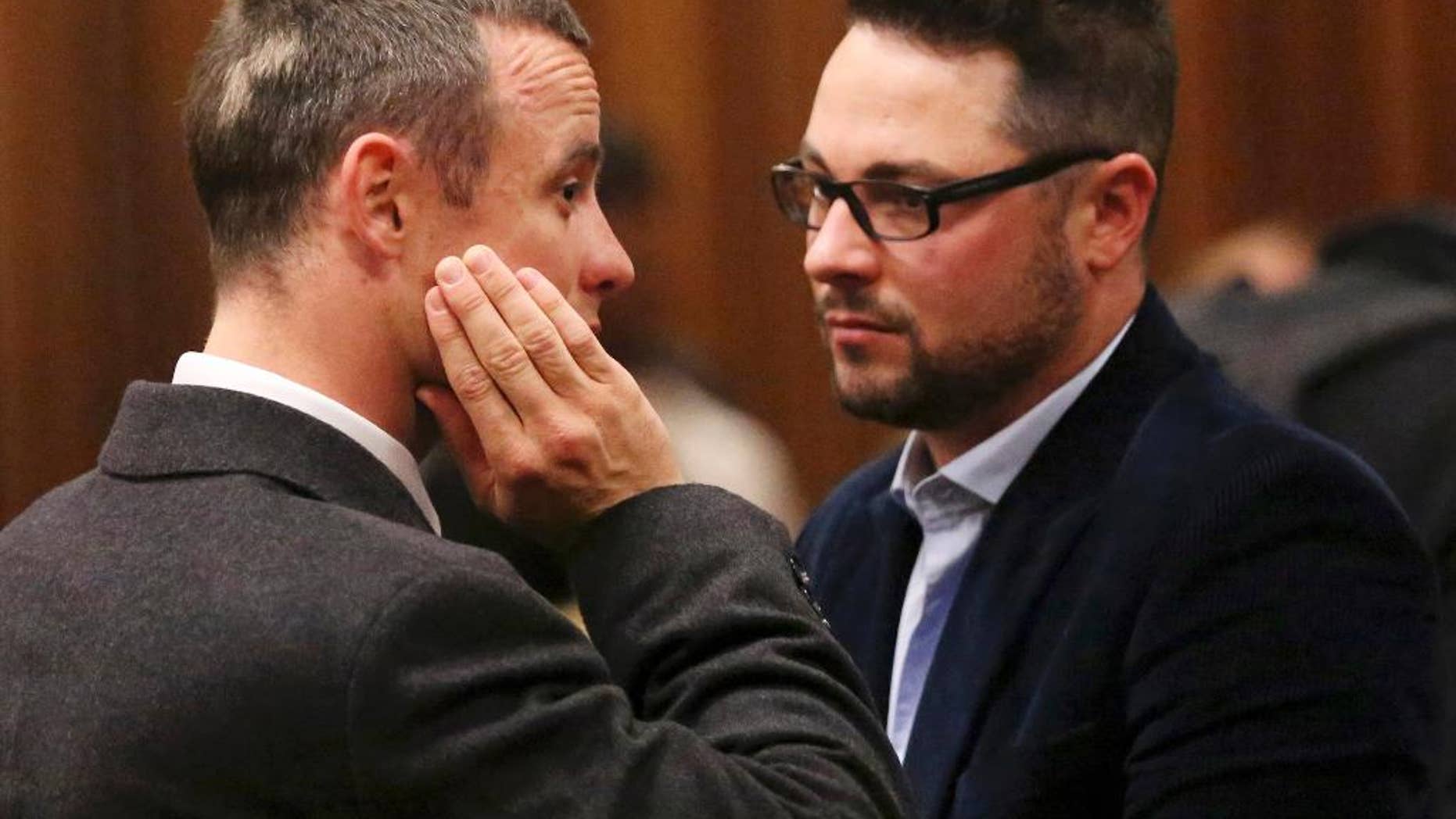 FILE - In this Tuesday May 20, 2014 file photo brother of murder accused, Oscar Pistorius, left, Carl Pistorius, right, speaks with his brother in court in Pretoria, South Africa. Aug. 1, 2014. Carl Pistorius has been discharged from an intensive care unit in the hospital after suffering internal injuries and going into respiratory failure following a car crash Aug. 1, 2014. (AP Photo/Siphiwe Sibeko, Pool, File)