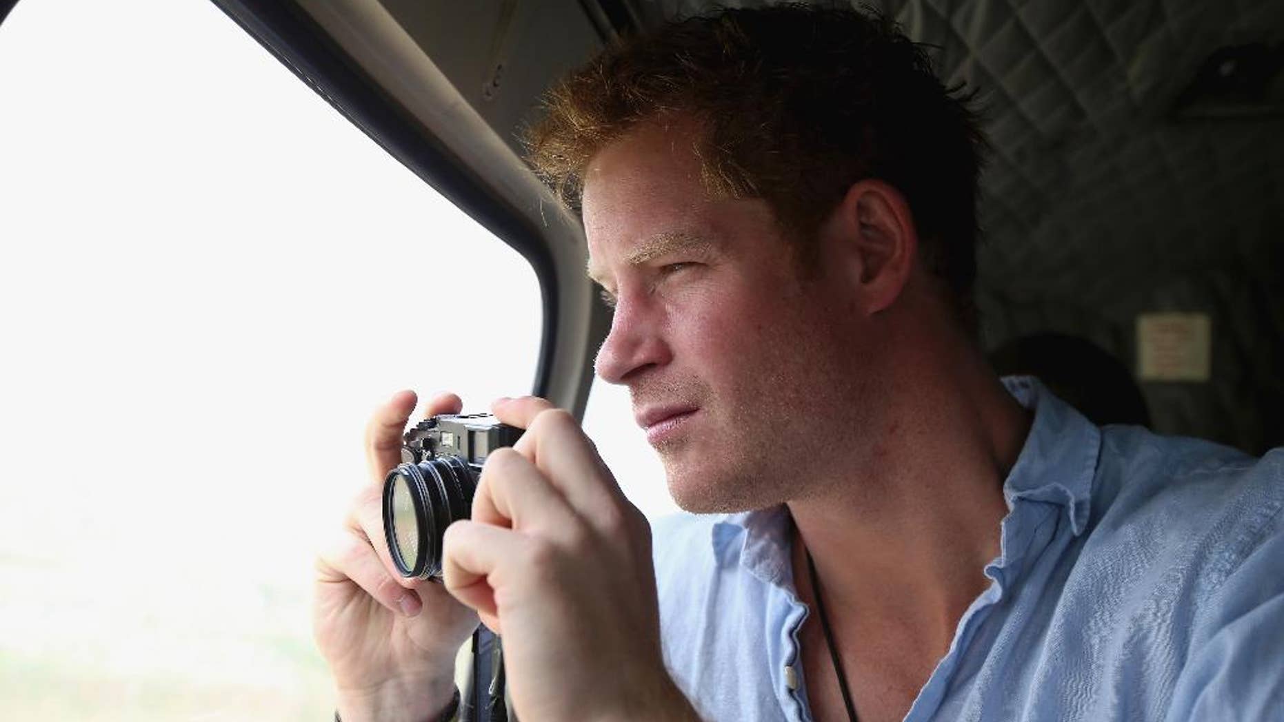 FILE - In this Dec 8, 2014, file photo, Prince Harry takes a photograph out of the window of a helicopter as he travels over the Muluti Mountains on his way to visit a herd boy night school constructed by his Sentebale charity, in Mokhotlong, Lesotho. Prince Harry has been on a private visit to Kruger National Park, South Africa's flagship wildlife park, where poachers have killed rhinos in record numbers and clashed with rangers, the service said in a statement emailed Thursday, Aug. 13, 2015, to The Associated Press. (Chris Jackson/Pool Photo via AP, File)