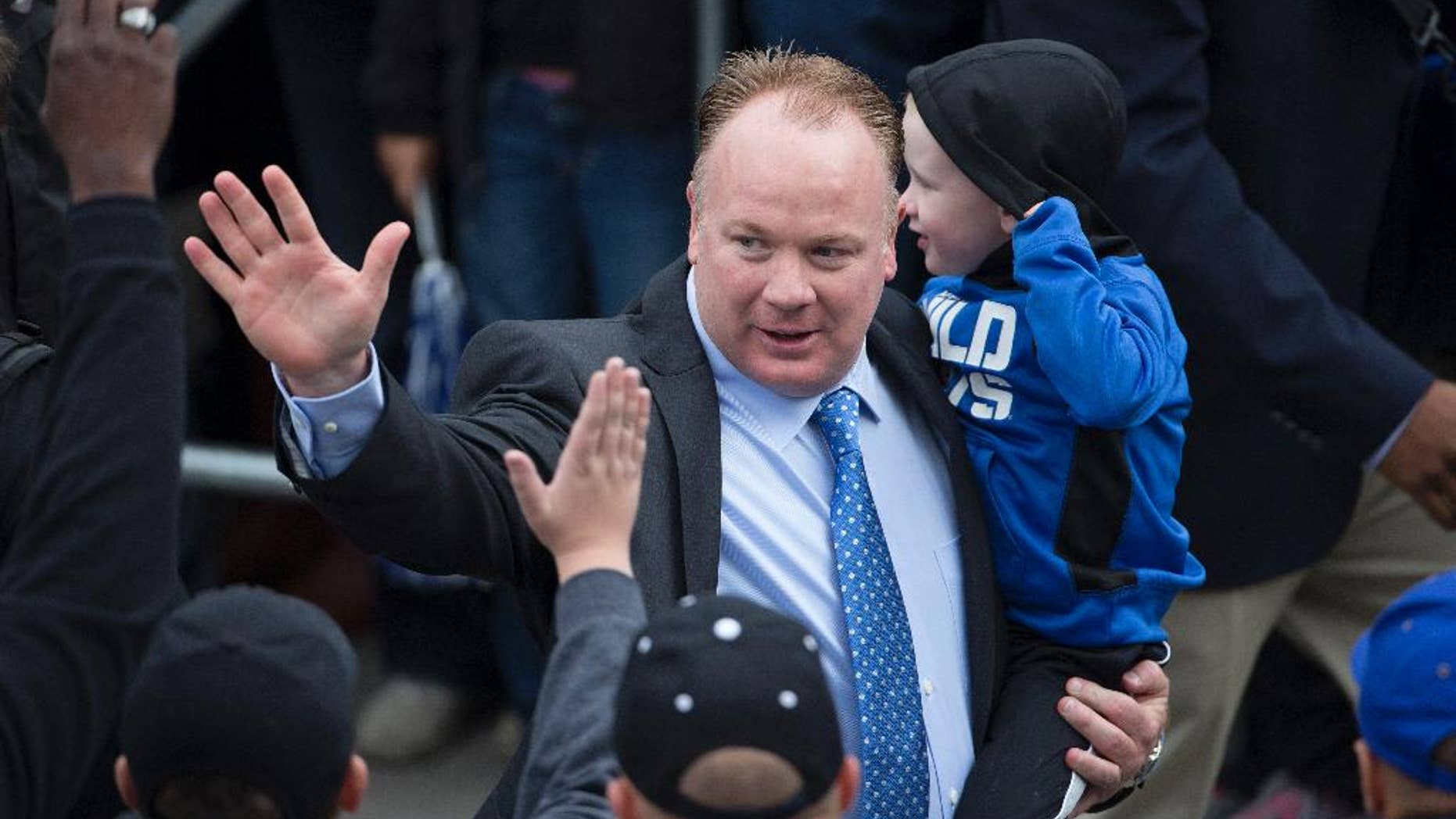 Kentucky head coach Mark Stoops, holding his son Zack, waves to fans as he walks into the stadium for an an NCAA college football game against South Carolina at Commonwealth Stadium in Lexington, Ky., Saturday, Oct. 4, 2014. (AP Photo/David Stephenson)