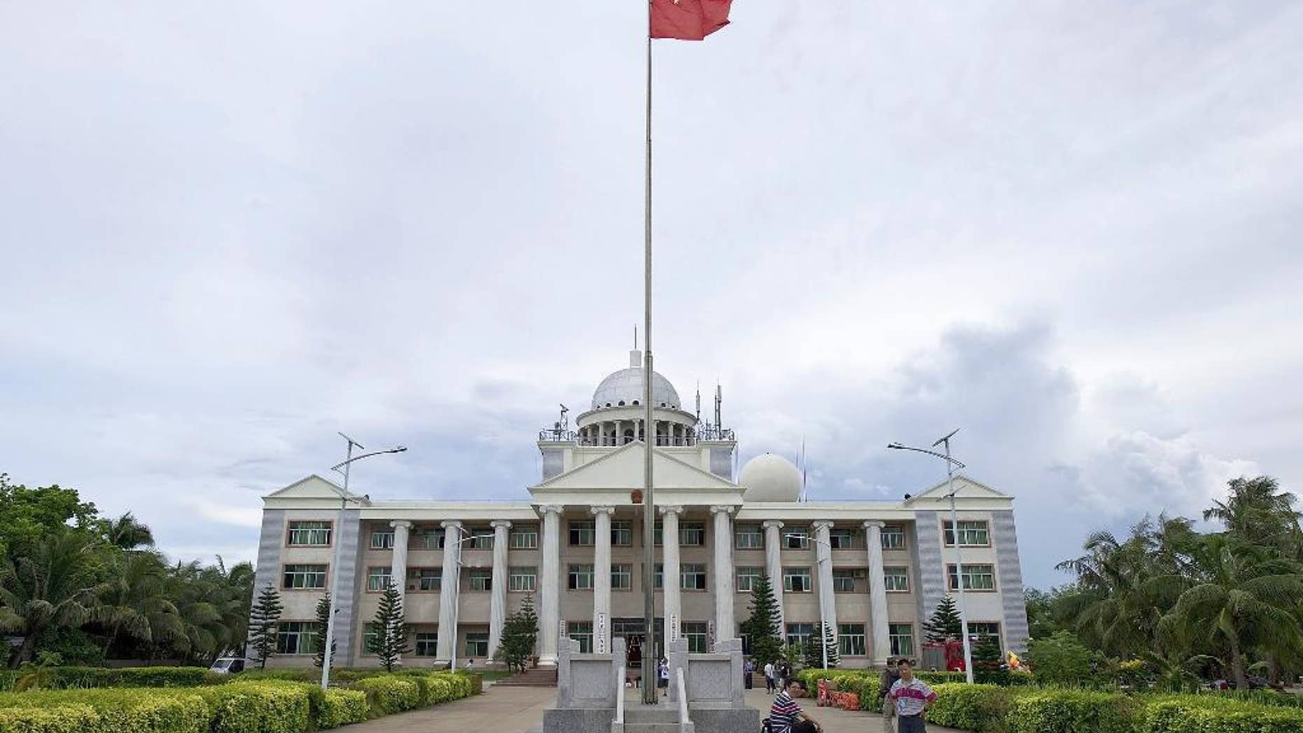 FILE - In this July 21, 2012 file photo, Chinese people chat in front of an administration office building for the Xisha, Nansha, Zhongsha islands on Yongxing Island, the government seat of Sansha City off the south China's Hainan province. China is building a school on the remote island in the South China Sea to serve the children of military personnel and others, deepening the facilities in the city it created in its campaign to claim the world's most disputed waters. (AP Photo/File) CHINA OUT