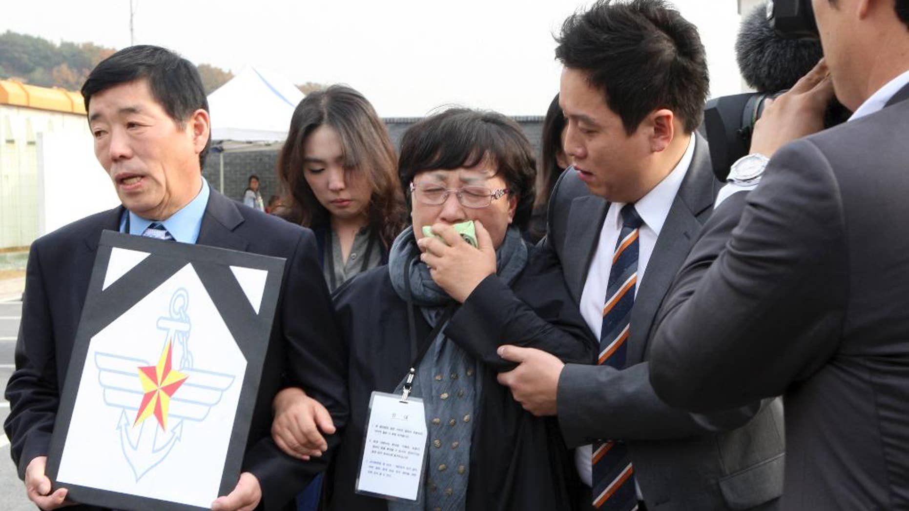 A mother, center, of a victim, identified as Private First Class Yoon, cries after the trial at an outside of military court in Yongin, south of Seoul, South Korea, Thursday, Oct. 30, 2014. South Korea's Defense Ministry says a military court has sentenced six soldiers to up to 45 years in prison for bullying and beating a subordinate who died. (AP Photo/Yonhap, Ryu Soo-hyun) KOREA OUT