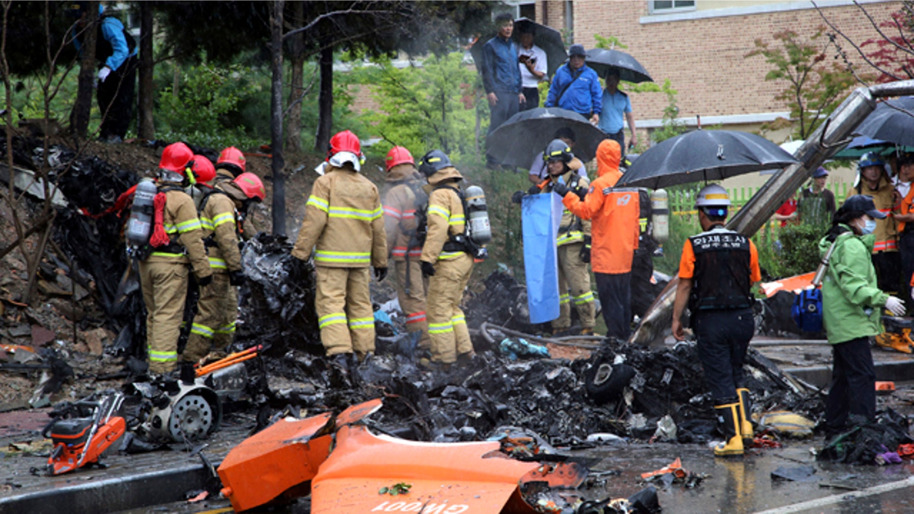 July 17, 2014: Firefighters inspect the wreckage of a helicopter which crashed near an apartment complex and school in Gwangju, South Korea. (AP Photo/Yonhap, Park Chul-hong)