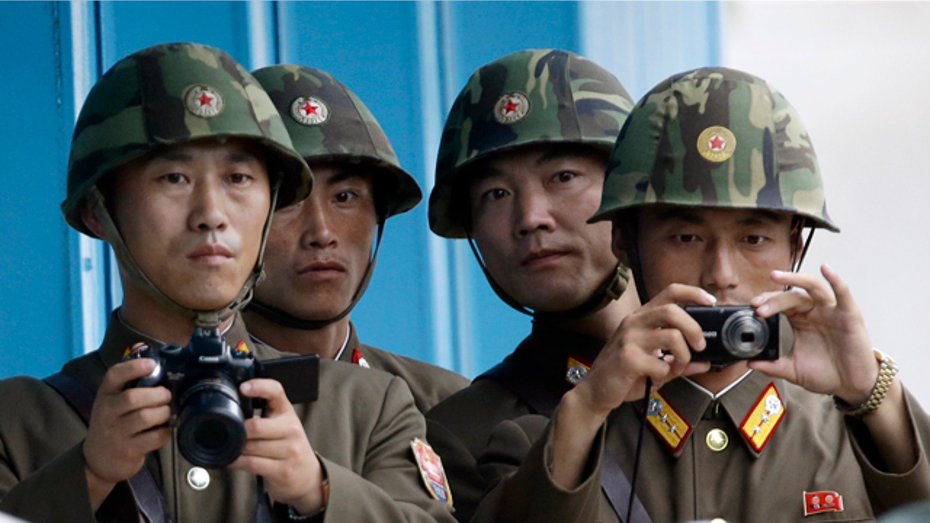 In this Saturday, July 27, 2013 photo, North Korean soldiers watch the southern side with cameras at the border village of Panmunjom, which has separated the two Koreas since the Korean War, in Paju, South Korea. (AP Photo/Lee Jin-man)