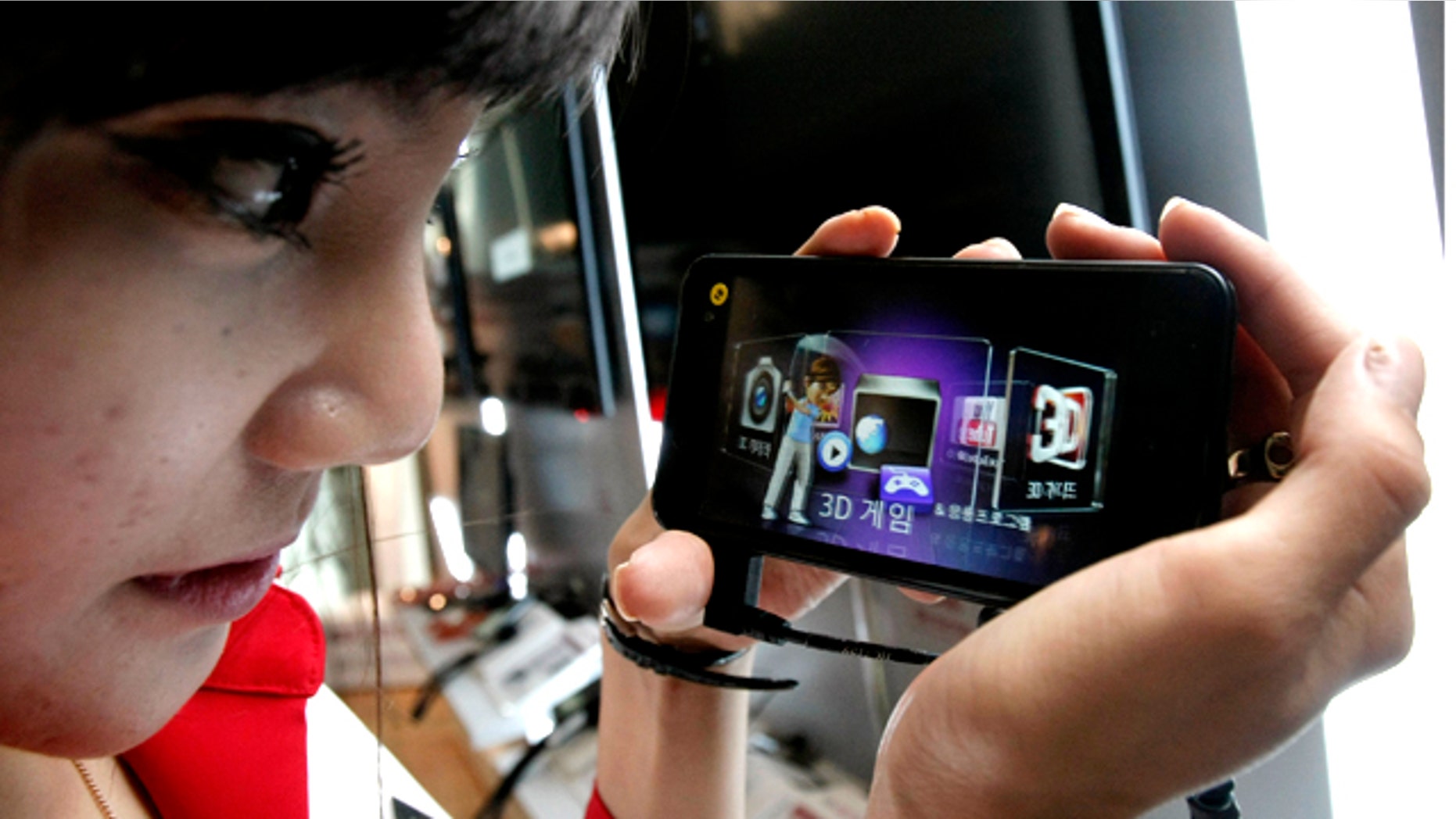 July 7, 2011: A model looks at an LG Electronics Optimus 3D phone during a press conference in Seoul, South Korea.
