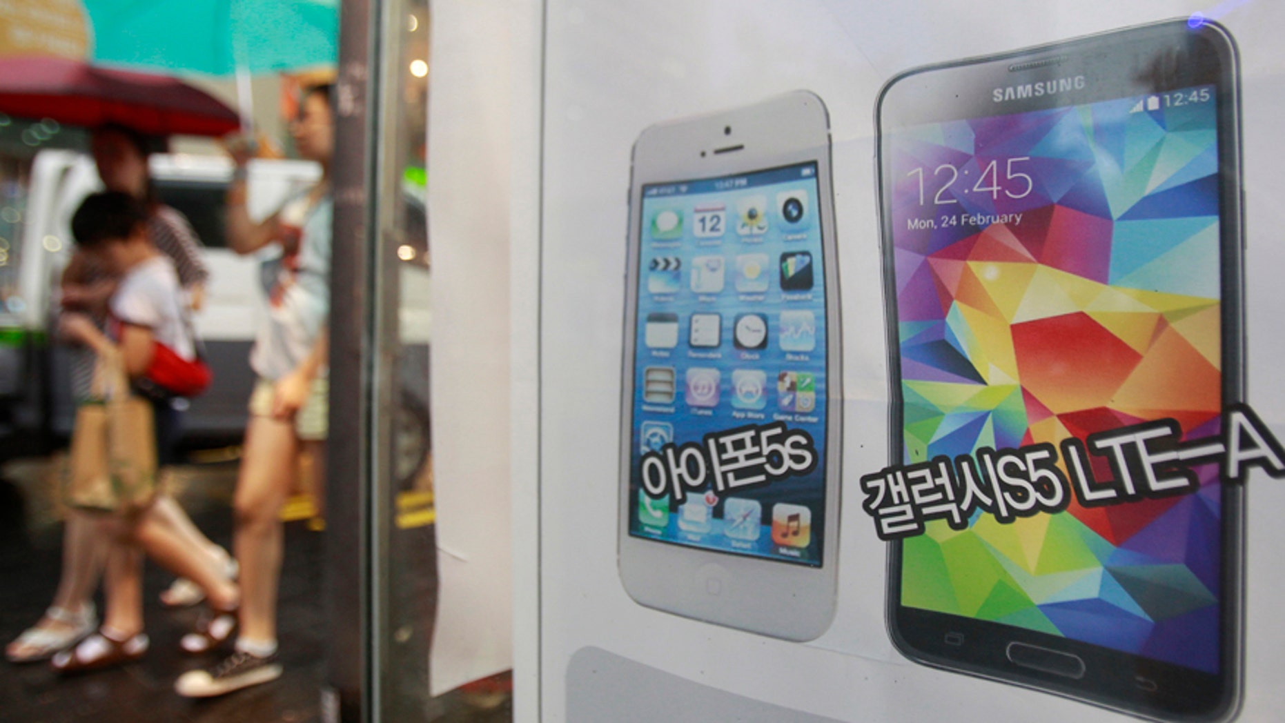 An advertisement poster shows Samsung Electronics' Galaxy S5 LTE-A, right, and Apple's iPhone 5s at a mobile phone shop in Seoul, South Korea, Wednesday, Aug. 6, 2014.