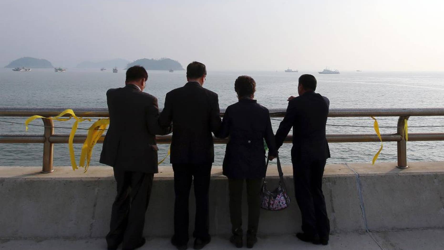 Christians pray near yellow ribbons with messages for the victims and missing passengers of the sunken ferry Sewol, at a port in Jindo, south of Seoul, South Korea, Monday, May 12, 2014. Bad weather prevented divers from searching inside the sunken, deteriorating South Korean ferry for a third day Monday. (AP Photo/Yonhap) KOREA OUT
