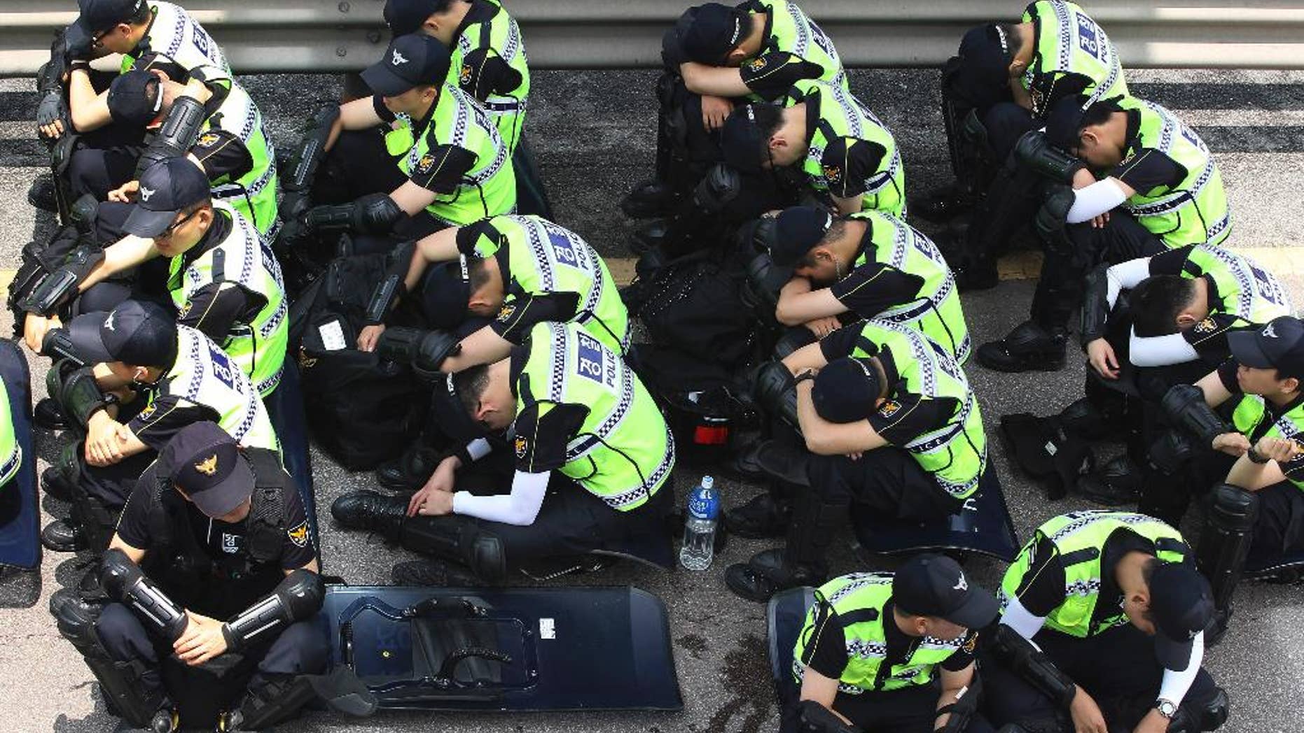 Police officers take a rest near Evangelical Baptist Church in Anseong, South Korea, Wednesday, June 11, 2014. Thousands of South Korean police officers stormed a church compound Wednesday in their hunt for a fugitive billionaire businessman over April's ferry sinking that left more than 300 people dead or missing, officials said. (AP Photo/Ahn Young-joon)