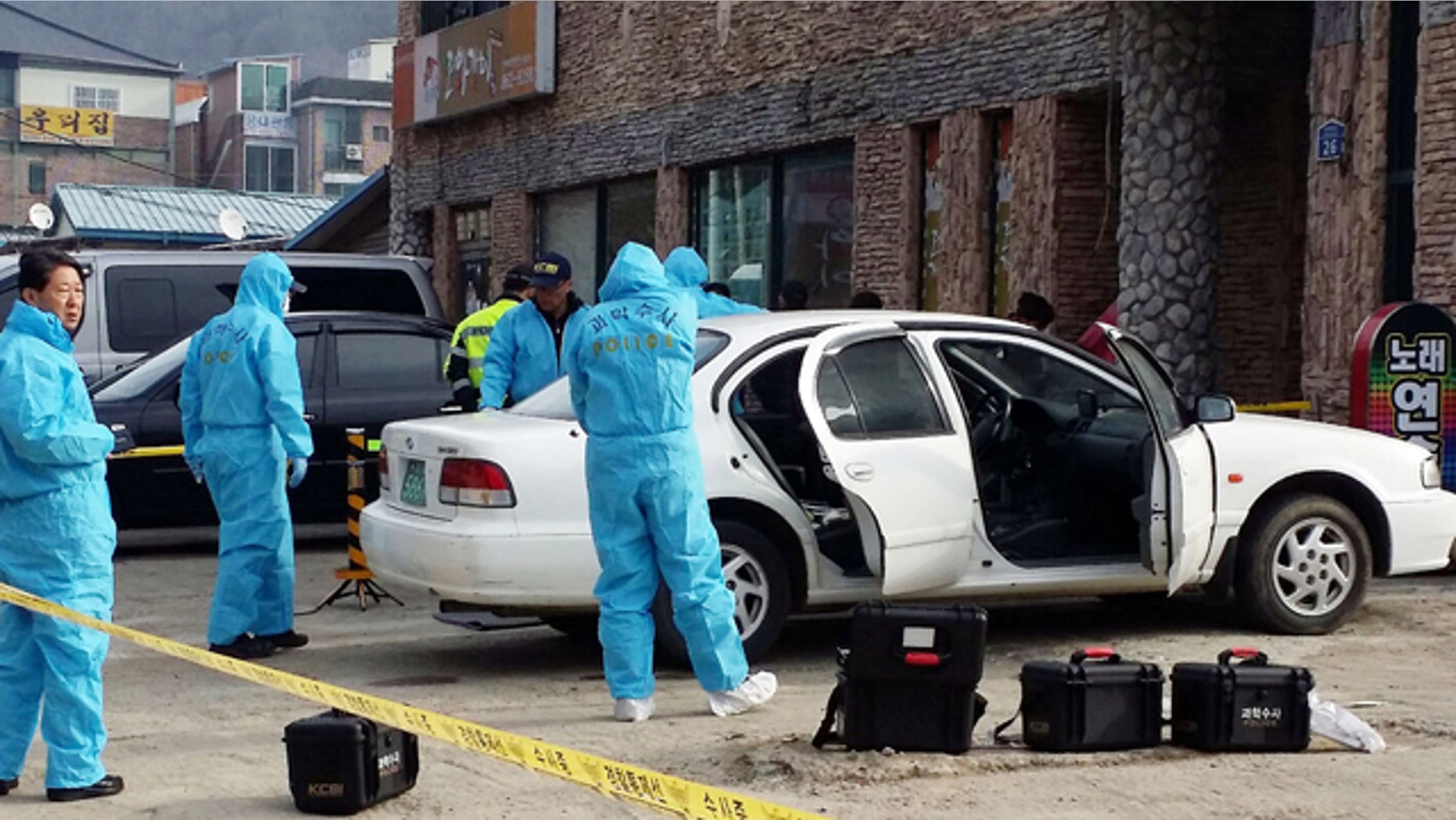 Feb. 25, 2015: South Korean police officers investigate a vehicle near the scene of an incident in Sejong, south of Seoul. South Korean police said Wednesday that three people were dead after a gunman opened fire at a store in Sejong City and set the store on fire before fleeing. (AP Photo/Yonhap, Lee Jae-lim)