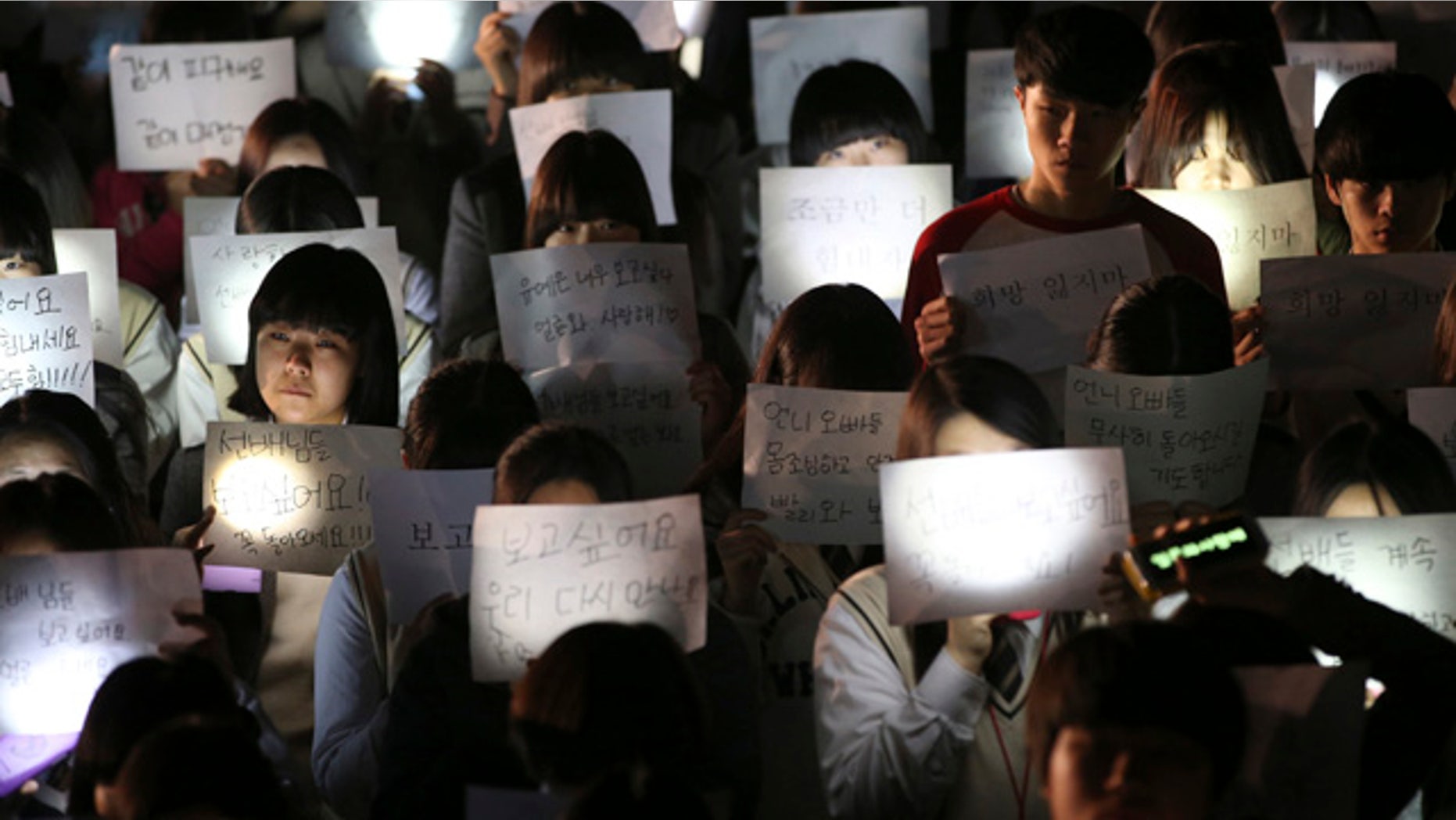 April 18, 2014: Students hold papers with candles as they pray for the safe return of their friends aboard the sunken ferry Sewol at Danwon High School in Ansan, south of Seoul, South Korea. (AP Photo/Yonhap)