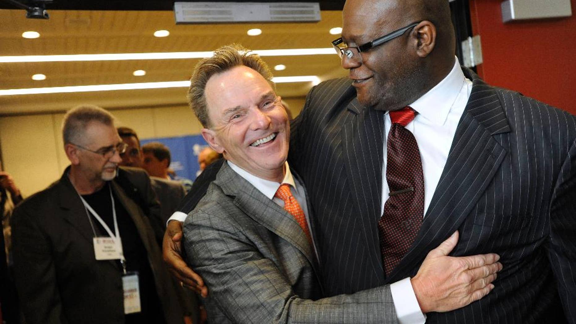 The Rev. Ronnie Floyd, center, of Cross Church in northwest Arkansas, hugs The Rev. Dwight McKissic, right, of Cornerstone Baptist Church in Arlington, Texas, after Floyd was elected the new president of the Southern Baptist Convention during its annual meeting Tuesday, June 10, 2014, in Baltimore. Floyd received 52 percent of votes cast by delegates to the annual meeting of the nation's largest Protestant denomination. (AP Photo/Steve Ruark)