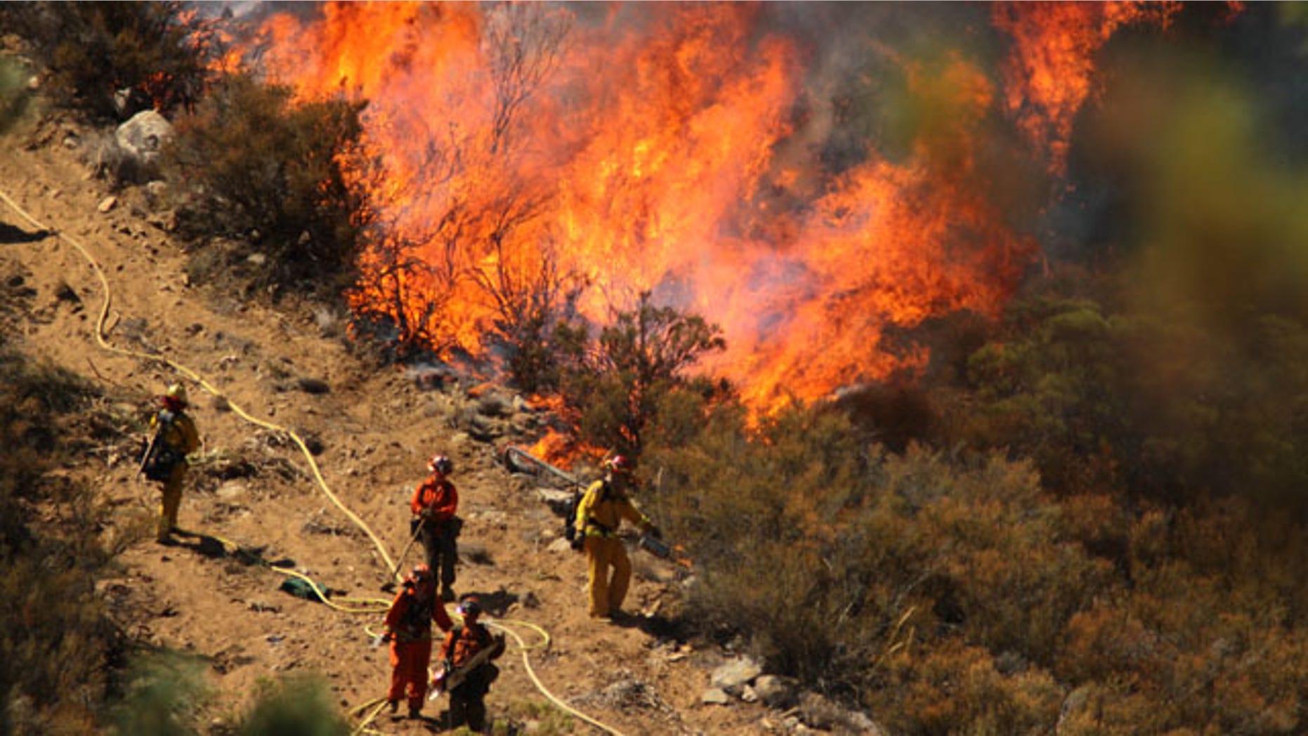 July 17, 2013: A female inmate hand crew from Puerta La Cruz and firefighters in an engine company with them set fire to reinforce the line to stave off part of the Mountain Fire burning up a hill toward them off Apple Canyon Road near Lake Hemet, Calif. Officials say the wildfire in the mountains west of Palm Springs has destroyed three houses and three mobile homes and is threatening dozens more residences. (AP Photo/The Desert Sun, Crystal Chatham)