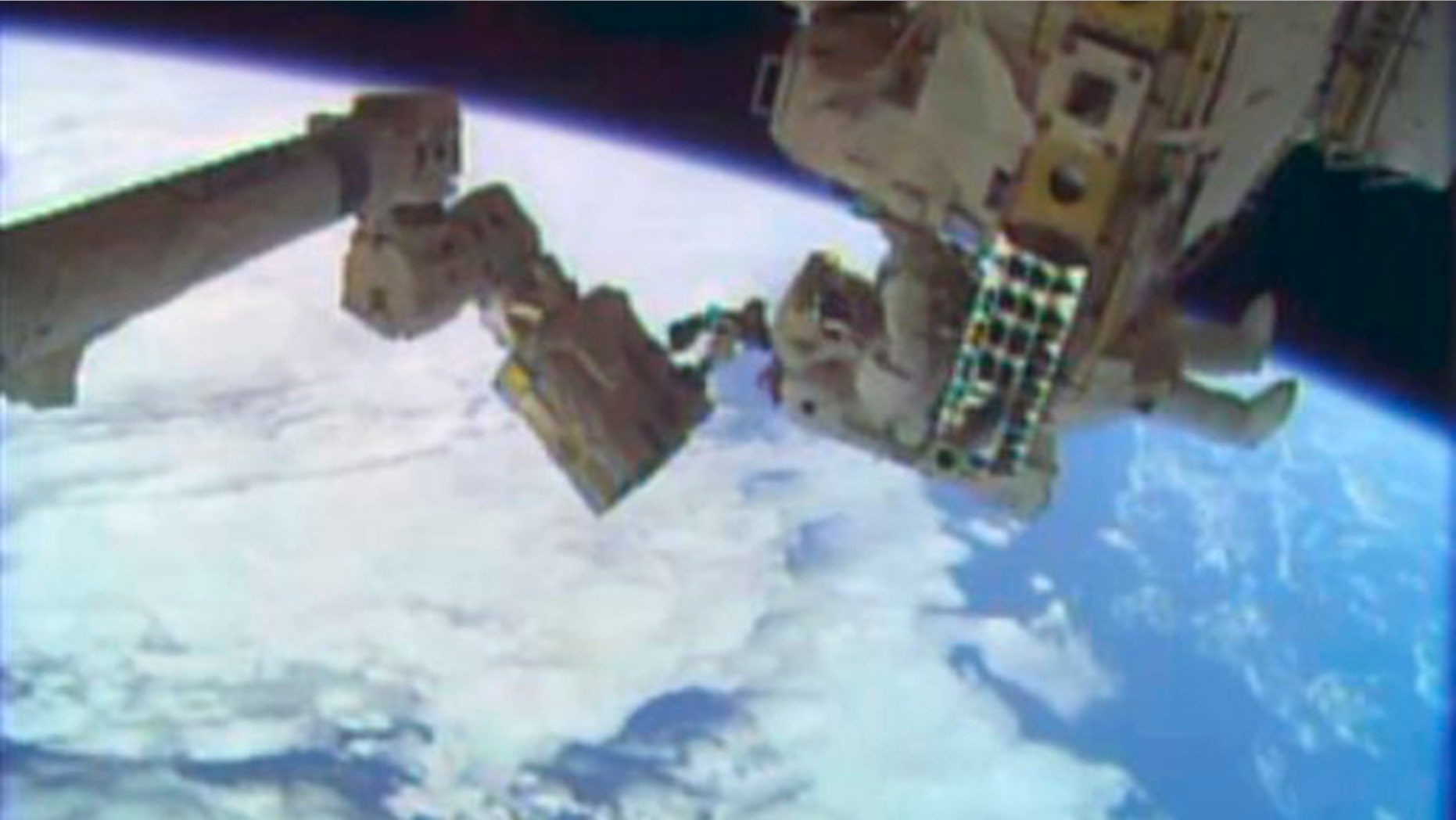In this image taken from video provided by NASA, astronauts Rick Mastracchio, top, and Michael Hopkins work to repair an external cooling line on the International Space Station on Monday, Dec. 24, 2013, 260 miles above Earth. The external cooling line â one of two â shut down Dec. 11. The six-man crew had to turn off all nonessential equipment, including experiments. (AP Photo/NASA)