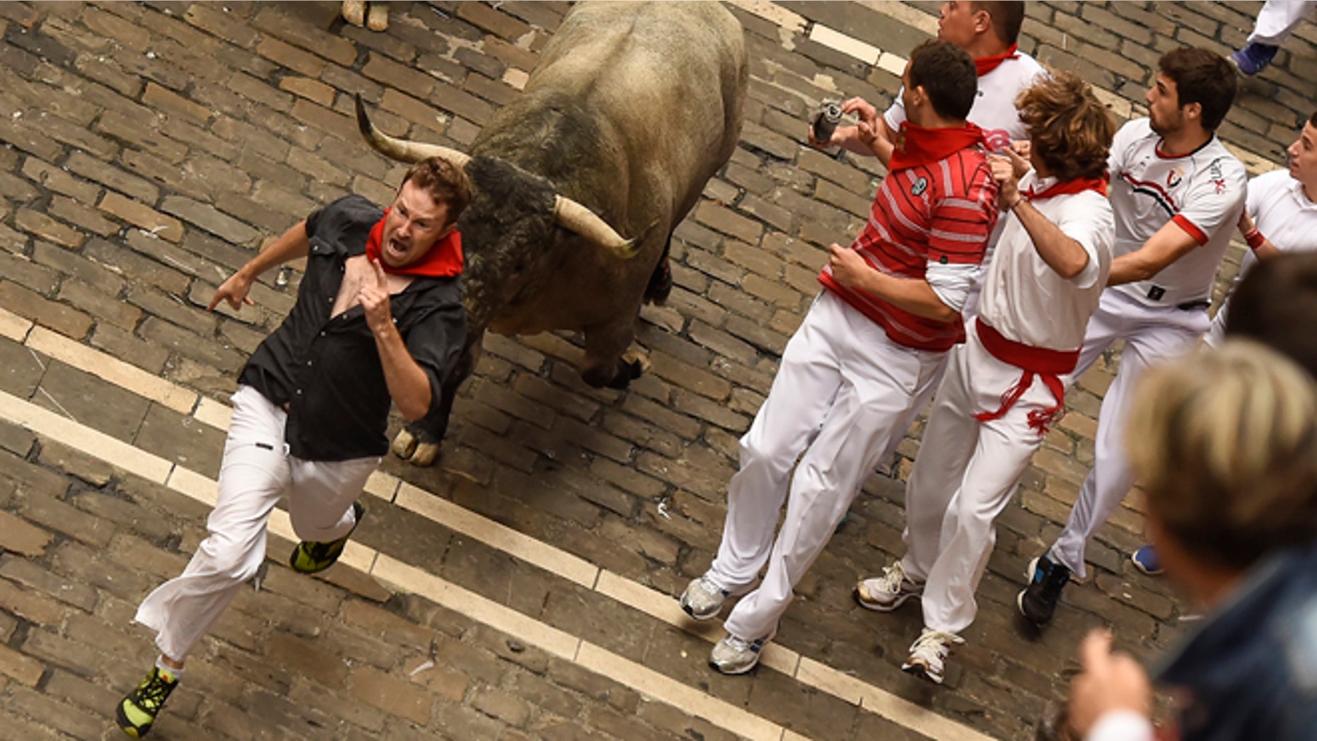 A participant runs in front of a ''Jose Escolar Gil'' fighting bull alongside Mercaderes street, during the fifth running of the bulls, at the San Fermin Festival, in Pamplona, Spain, Saturday, July 11, 2015. Revelers from around the world arrive to Pamplona every year to take part in some of the eight days of the running of the bulls. (AP Photo/Alvaro Barrientos)