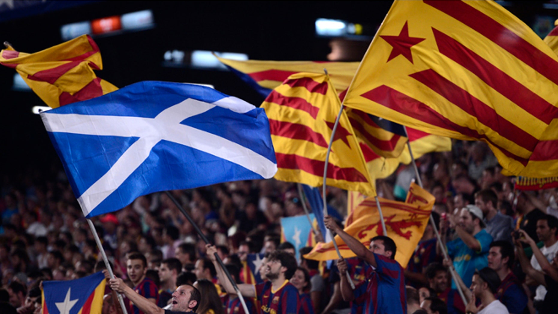 A fan waves a Scottish national flag alongside others waving 'Estelada' flags, that symbolize Catalonia's independence during the Champions League Group F soccer match between Barcelona and Apoel at the Camp Nou stadium in Barcelona, Spain, Wednesday, Sept. 17, 2014. (AP Photo/Manu Fernandez)