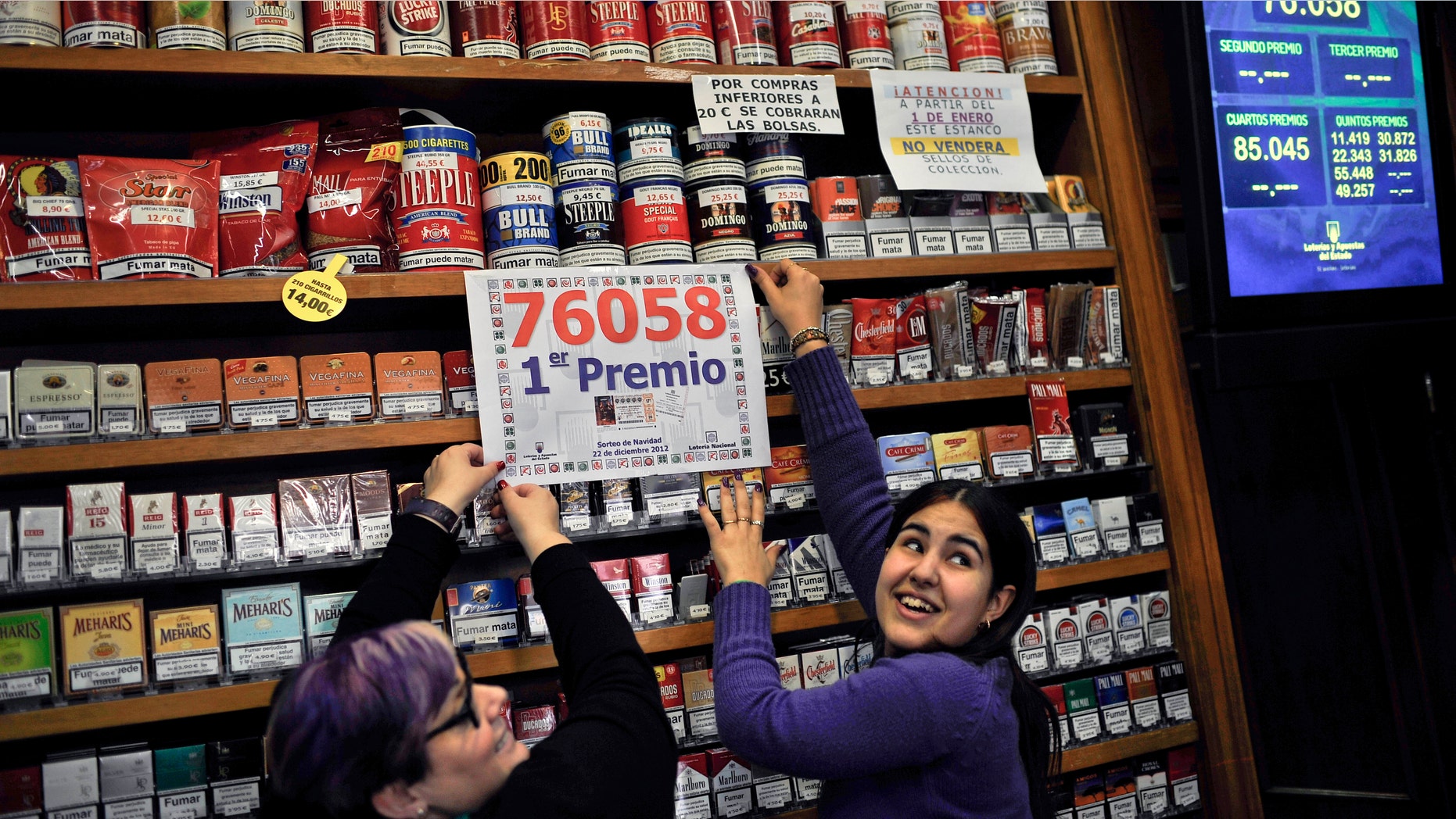 Laura Leon, 30, right, and Pili Medina, 48, who sold one of the winning lottery tickets with the numbers, 76058, of the top prize of Spain's Christmas lottery known as "El Gordo" or "The Fat One" number, celebrates this, in her lottery shop, in the small town of Tudela, northern Spain on Saturday Dec. 22, 2012, around 300 kilometers from Madrid. (AP Photo/Alvaro Barrientos)