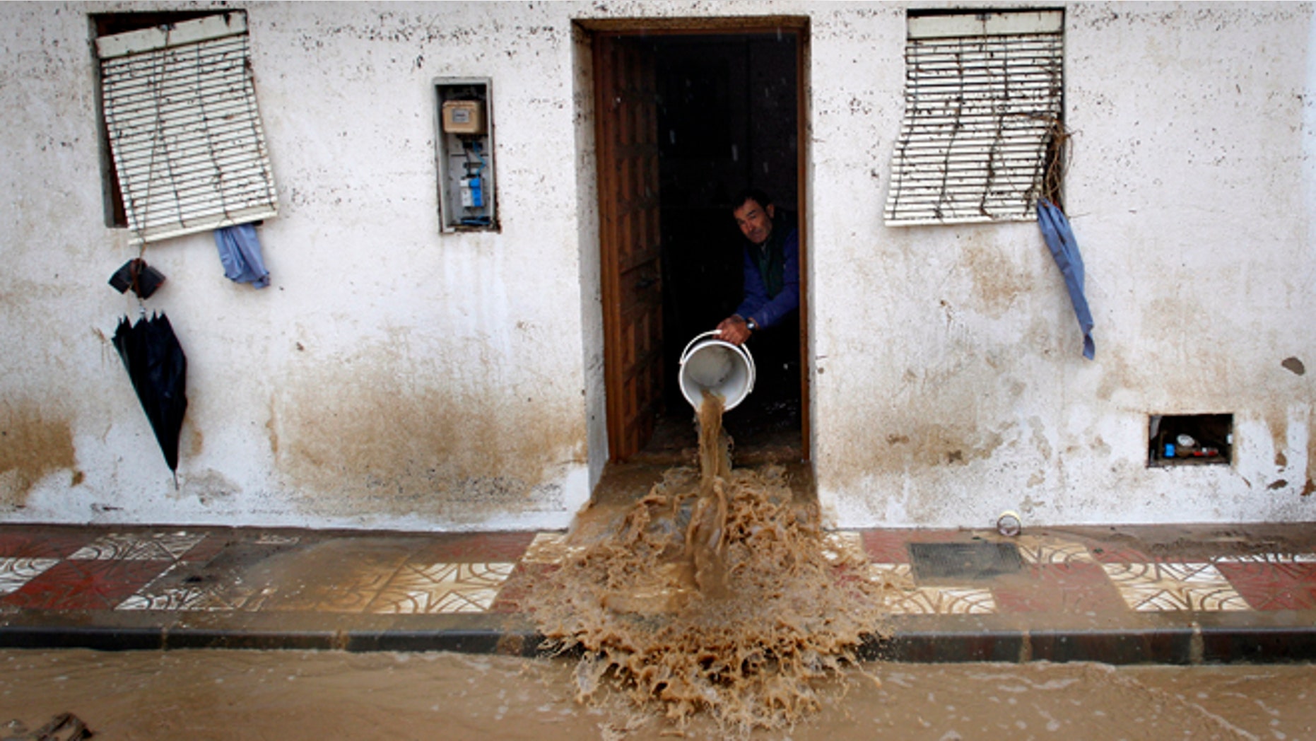 A man to clear muddy water from his house, after heavy rain caused flash floods in the town of Villanueva del Rosario, Malaga, southern Spain, Friday, Sept. 28, 2012. Homes were destroyed and at least one woman was killed. Rescue workers are searching to determine if there are more victims. (AP Photo/Sergio Torres)