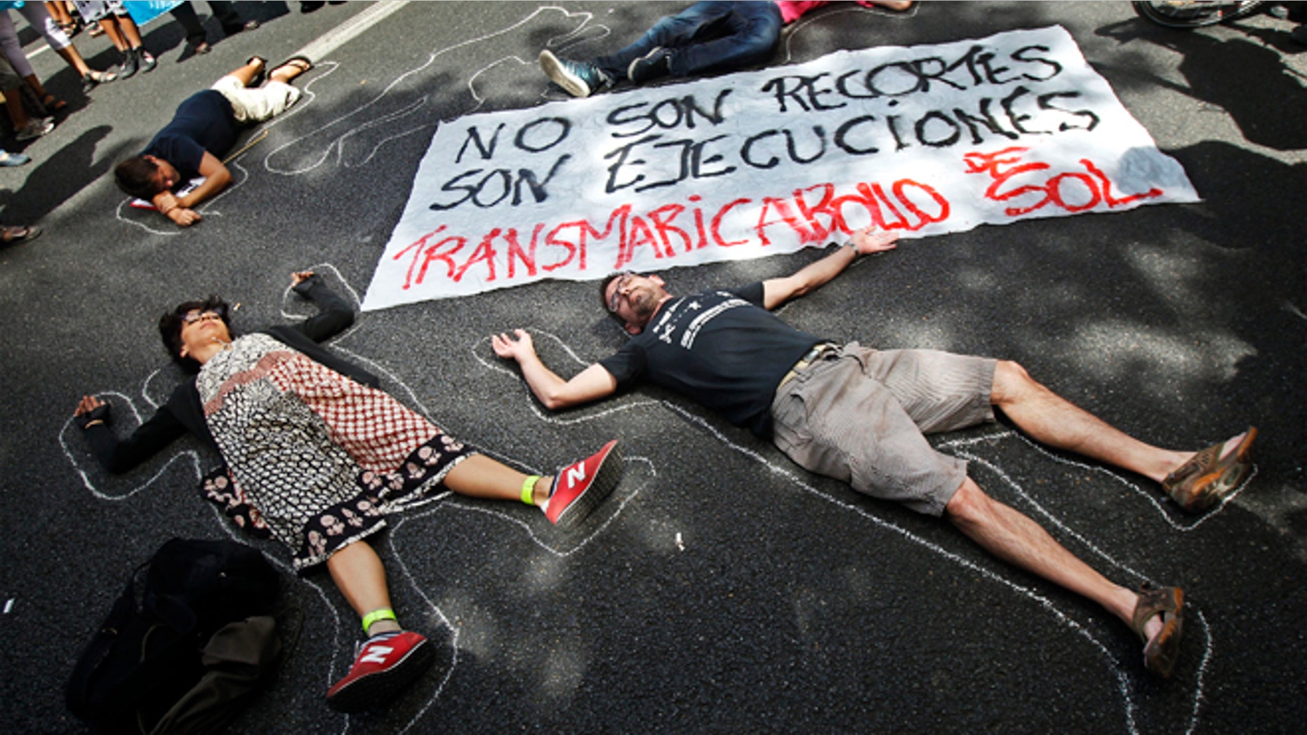 People perform showing a banner reading "they are not financial cuts but executions", against healthcare austerity measures announced by the Spanish government in Madrid, Spain, Saturday, Sept. 1, 2012. Some 300 people have blocked a ring road in Madrid to protest the introduction of spending cuts that will leave more than 150,000 non-registered immigrants without healthcare in Spain. Illegal immigrants who do not contribute taxes to social security are, as of Saturday, to lose national health cards that had entitled them to free treatment in case of illness. (AP Photo/Andres Kudacki)