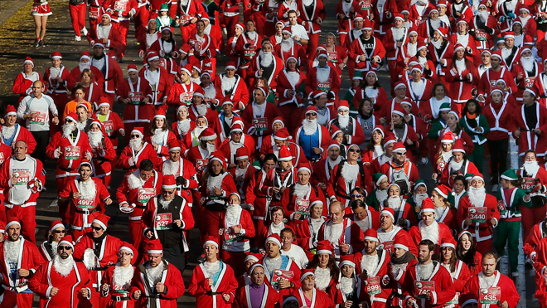 Revelers dressed as Santa Claus run during a "mini-marathon" in Madrid, Spain, Saturday, Dec. 14, 2013. Around 6,000 people dressed as Santa Claus and his elves have run a âmini-marathonâ through the streets of Madrid to promote festive cheer as the country tries to emerge from a two-year recession. While grown-ups dressed in red costumes with wispy white beards, children donned green elf outfits to run the 5.5 kilometer (3.4 miles) course through the city center. The race was organized Saturday by one of Spainâs leading department stores and it contributed 1 euro ($1.34) for each entrant to a charity that buys Christmas presents for deprived children around the world. (AP Photo/Andres Kudacki)