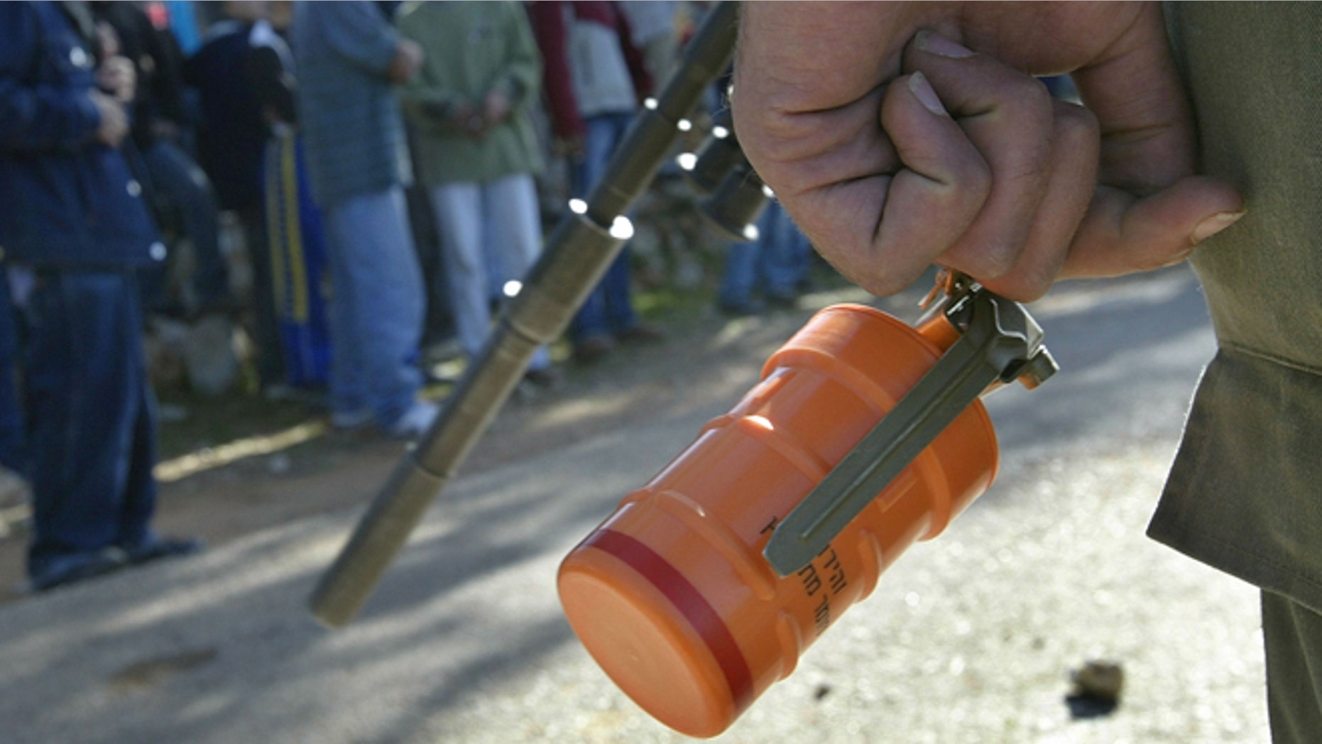 BUDRUS, WEST BANK - JANUARY 4: An Israeli border policeman holds a stun-grenade during a protest by Palestinians demonstrators January 4, 2004 against the construction of Israel's separation fence on their land at the West Bank village of Budrus. Israeli Justice Minister Yosef Lapid warned that Israel, because of its barrier, could be liable to international boycotts similar to those placed on South Africa during its apartheid regime. (Photo by David Silverman/Getty Images)