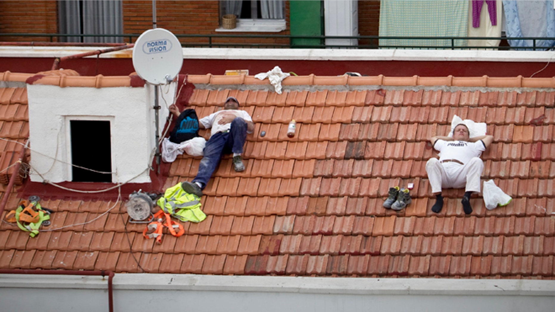 In this Oct. 10, 2012 file photo, workers take a nap on a roof in Madrid, Spain.