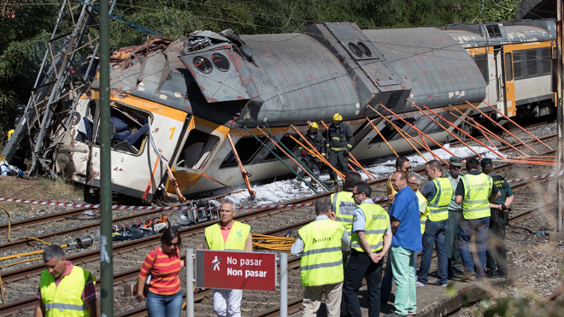 Emergency personnel attend the scene after a passenger train traveling from Vigo to Porto, in neighboring Portugal, derailed in O Porrino, in Spain's northwestern Galicia region, killing and injuring people, authorities said Friday Sept. 9, 2016. The train had three cars. The front one came completely off the track and hit a post next to the line, leaving it leaning to one side. The back two cars were partly off the tracks. Spanish media said the train was carrying around 60 passengers.(AP Photo/Lalo R. Villar)
