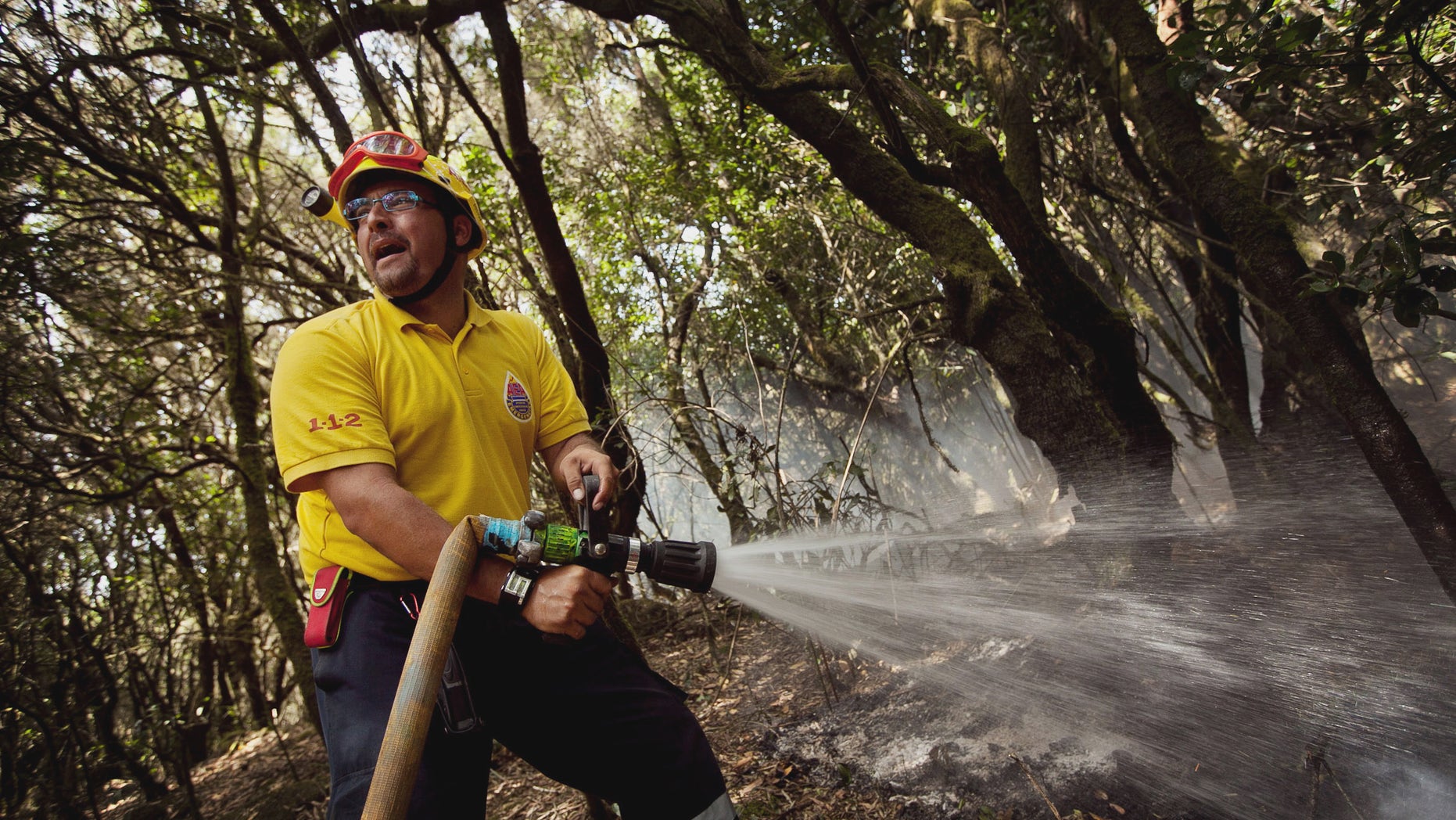 A firefighter works to halt the spread of wildfires in the Garajonay National Park, La Gomera, Spain, Sunday, Aug. 12, 2012. Wildfires spurred by high temperatures raged across Spain's Canary Islands of La Gomera and Tenerife as well as Ourense in northwestern Spain. Flames are threatening some of Europe's oldest surviving forests in the Garajonay National Park in La Gomera and have forced the evacuation of hundreds of people across the country. (AP Photo/Andres Gutierrez)