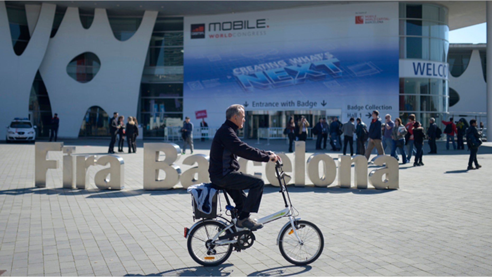 A man rides his bicycle outside the Mobile World Congress, the world's largest mobile phone trade show in Barcelona, Spain, Sunday, Feb. 23, 2014.