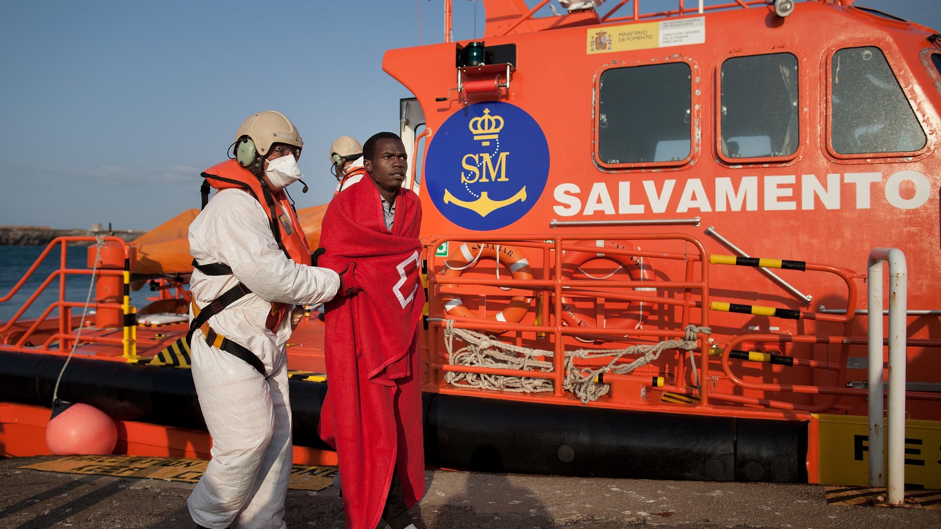 A coast guard from the Spanish Maritime Safety Agency helps a would-be immigrants to disembark at Tarifa Port after a rescue during high seas when they were sailing on an inflatable raft on August 30, 2013 in Tarifa, Spain. (Photo by Pablo Blazquez Dominguez/Getty Images)