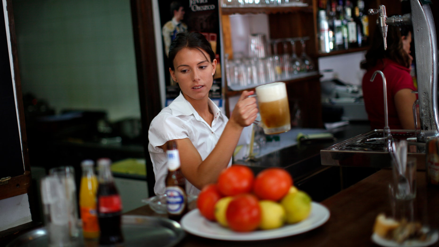 July 24, 2014: Olalla Gomez, 22, a final-year student of English philology who is also on on the first day of her probation period before getting a contract as temporary waiter, holds a mug of beer in the "Los Capeas" restaurant in downtown Ronda, near Malaga, southern Spain.