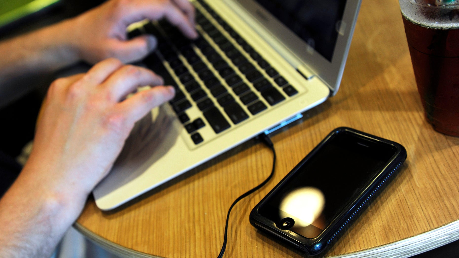 ** FOR USE MONDAY, DEC. 28 AND THEREAFTER ** FILE - In this May 13, 2009, file photo, Jonathan Hutcheson works on his laptop as his iPhone lays beside it at a coffee shop in Columbia, Mo. Wireless phone companies fear they're in danger of running out of room within the spectrum of wireless frequencies, so they want the government to give them bigger slices of airwaves _ even if other users have to give up rights to theirs. (AP Photo/L.G. Patterson, File)