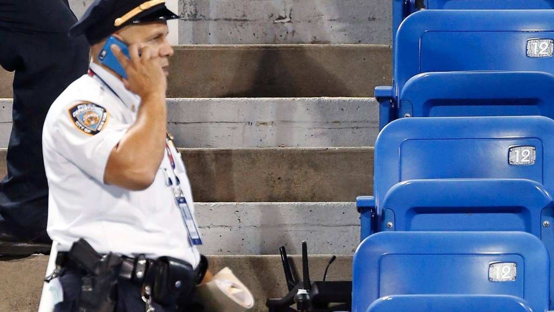 In this photo taken on Thursday, Sept. 3, 2015, police officers investigate the southwest corner of Louis Armstrong Stadium after a drone flew over the court, buzzing the players during a match between Flavia Pennetta, of Italy, and Monica Niculescu, of Romania, during the second round of the U.S. Open tennis tournament in New York. The drone crash-landed in the seats and can be seen to the right of the police officer on his phone. Whether they're crashing into the bleachers or simply hovering above stadiums to get a cool picture of the action down below, drones have become semi-regular guests at the ballparks these days. That has put the federal government, local police forces and security think tanks on alert, trying to catch up to the technology and figure out how to prevent the hard-to-stop devices from doing major damage. (AP Photo/Kathy Willens)