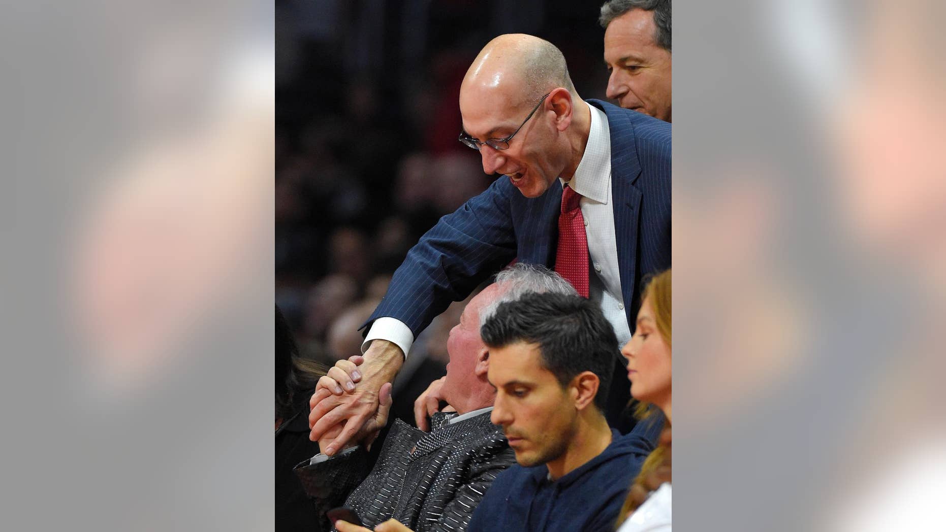 National Basketball Association commissioner Adam Silver greets San Antonio Spurs owner Peter Holt as they watch ;the Spurs play the Los Angeles Clippers during the first half of an NBA basketball game, Monday, Nov. 10, 2014, in Los Angeles. (AP Photo/Mark J. Terrill)
