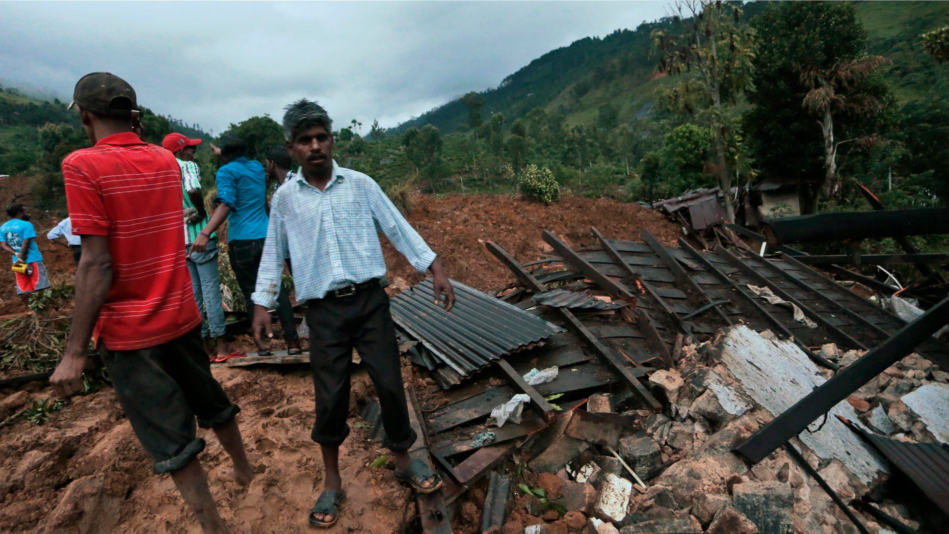 Oct. 29, 2014: Sri Lankans stand at the site of a mudslide at the Koslanda tea plantation in Badulla district,