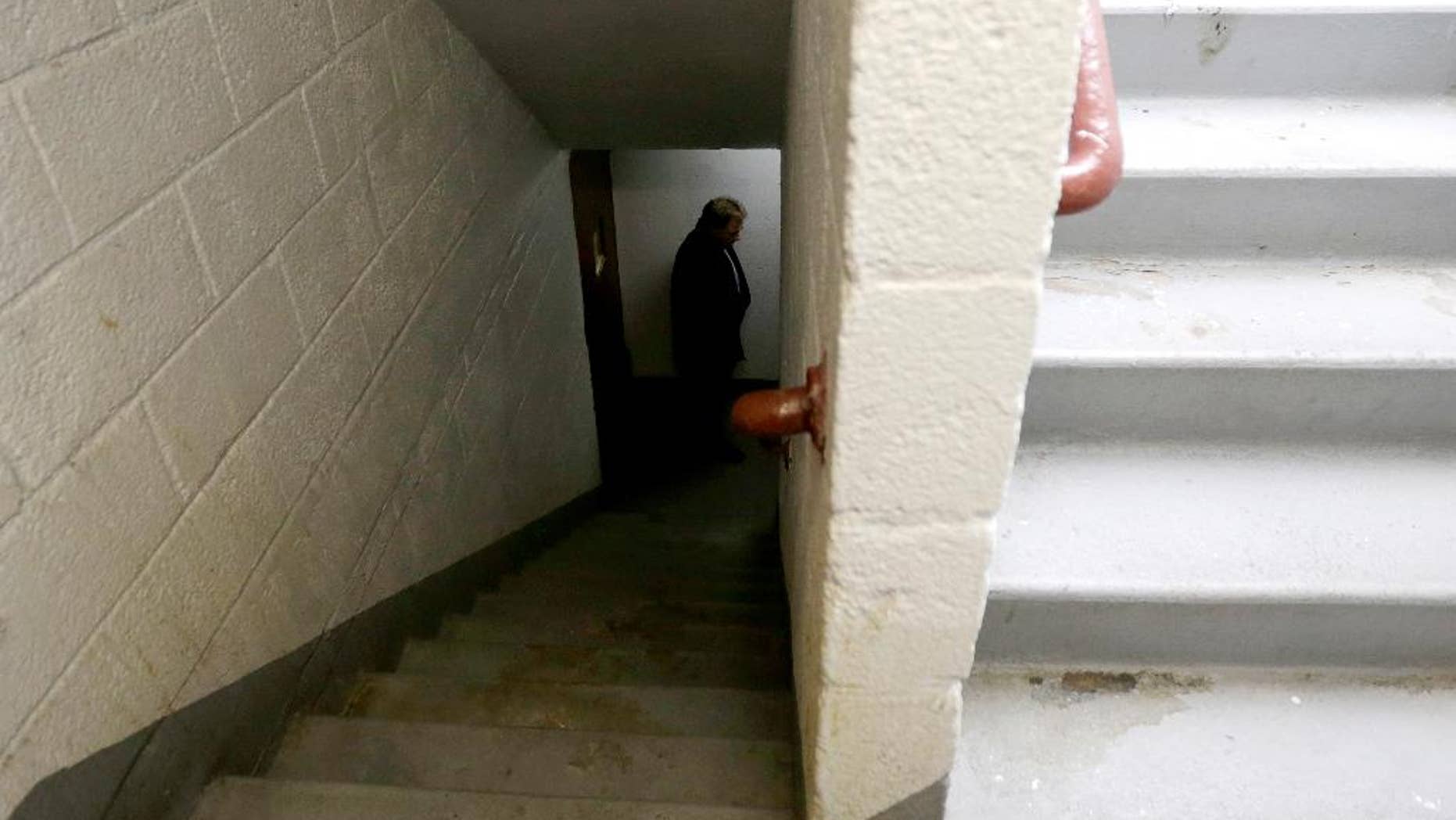 FILE - In this Nov. 21, 2014, file photo, a man who identified himself as a detective with the district attorney's office inspects a stairwell at the Louis Pink Houses public housing complex in Brooklyn borough of New York. Officer Peter Liang who fired into the darkened stairwell, accidentally killing Akai Gurley who had been waiting for an elevator, has been indicted in his death, a lawyer said Tuesday, Feb. 10, 2015. Liang will appear in court Wednesday according to an attorney representing Gurley's family, but the charges against Liang weren't immediately clear. (AP Photo/Julio Cortez, File)
