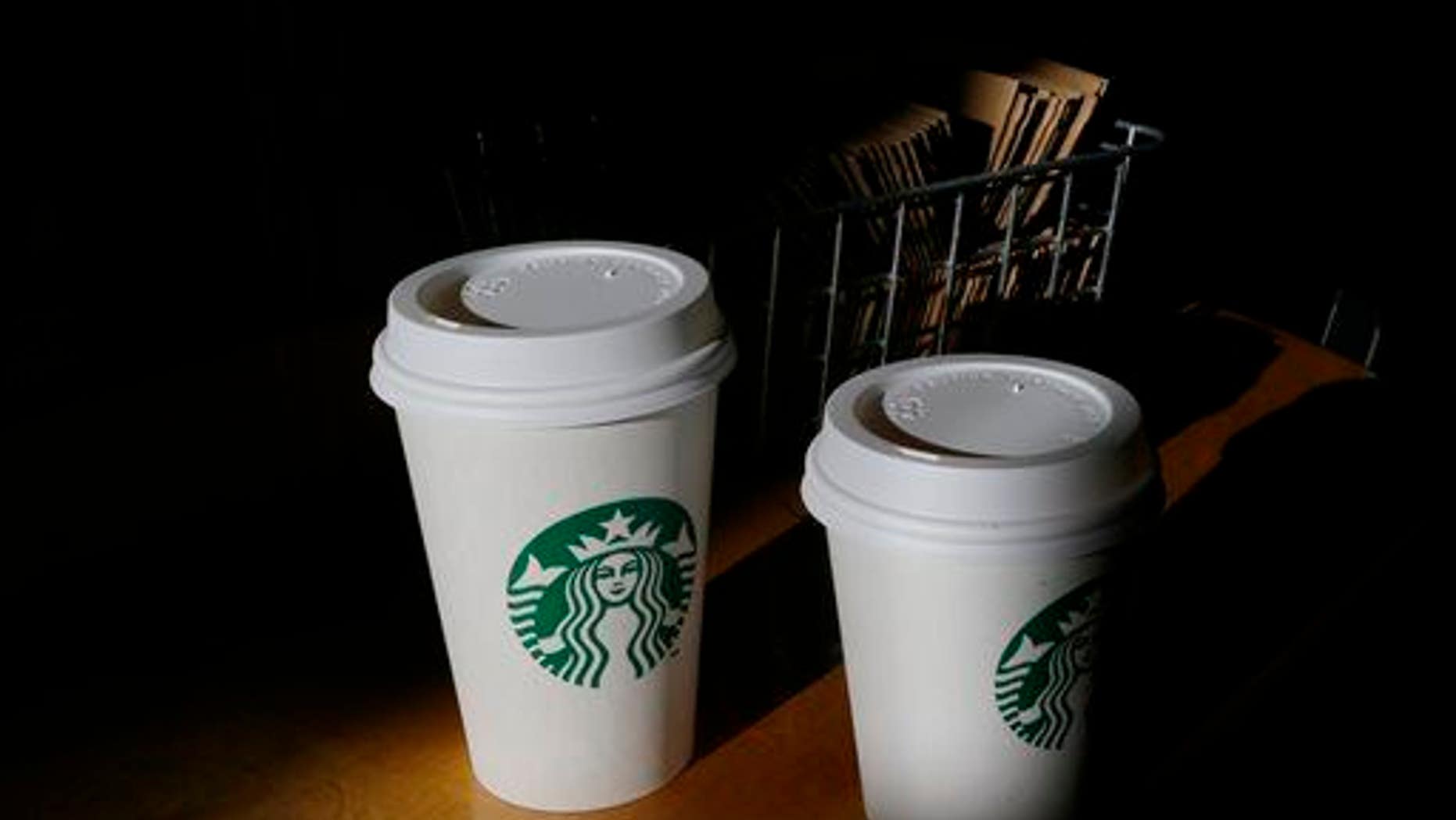 In this Wednesday, Oct. 23, 2013, file photo, cups of Starbucks coffee drinks sit on a counter at a Starbucks store, in Seattle.