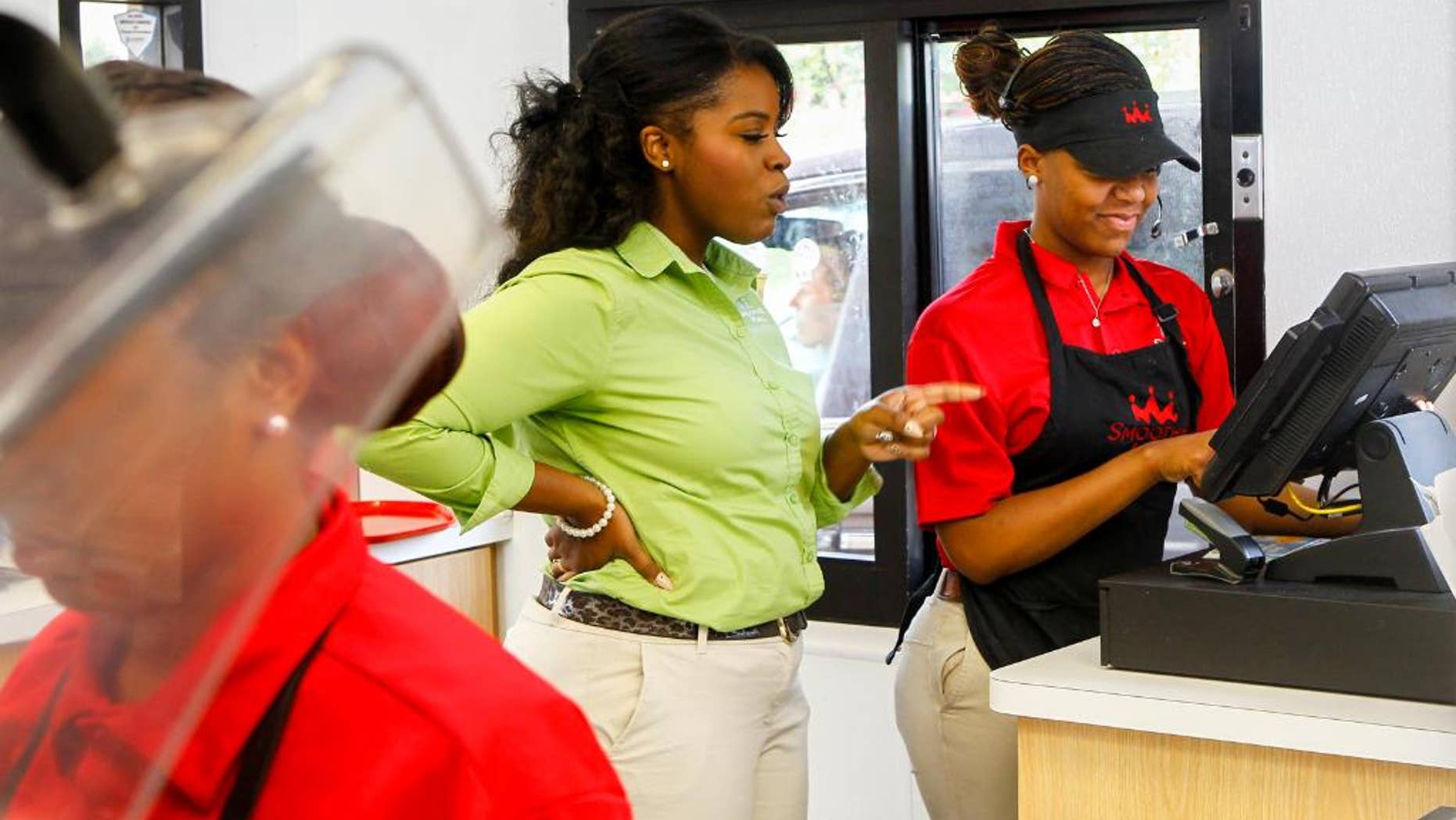 In this July 31, 2014 photo, Quamisha Nelson, owner and operator of the Smoothie King in Jacksonville, N.C., center, works alongside Latasia White, 15, as she rings up a customer's order at the drive-thru. The government reports on state unemployment rates for July on Monday, Aug. 18, 2014. (AP Photo/The Jacksonville Daily News, John Sudbrink)